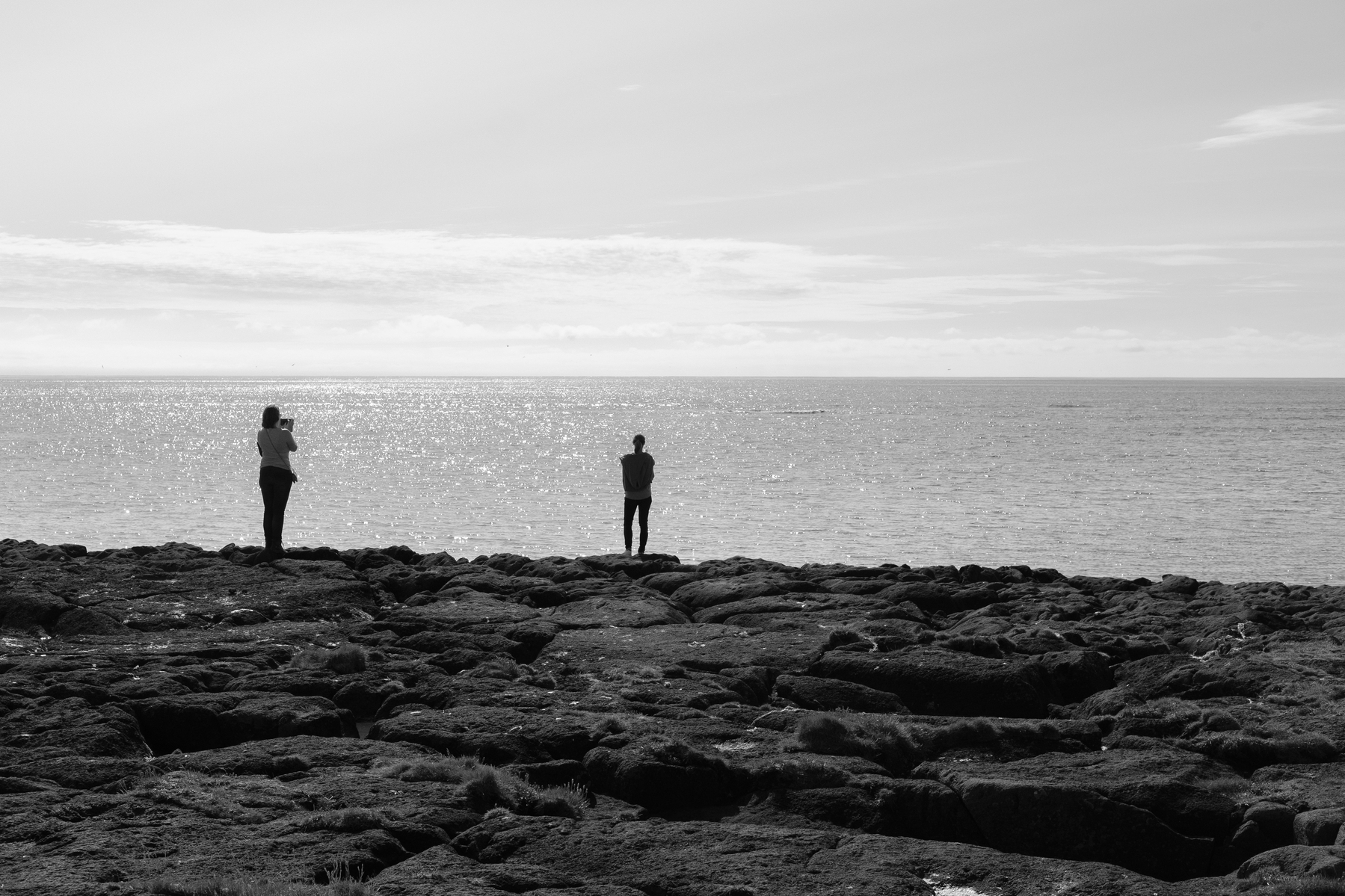 Tourists stand on a cliff and stare out to sea.