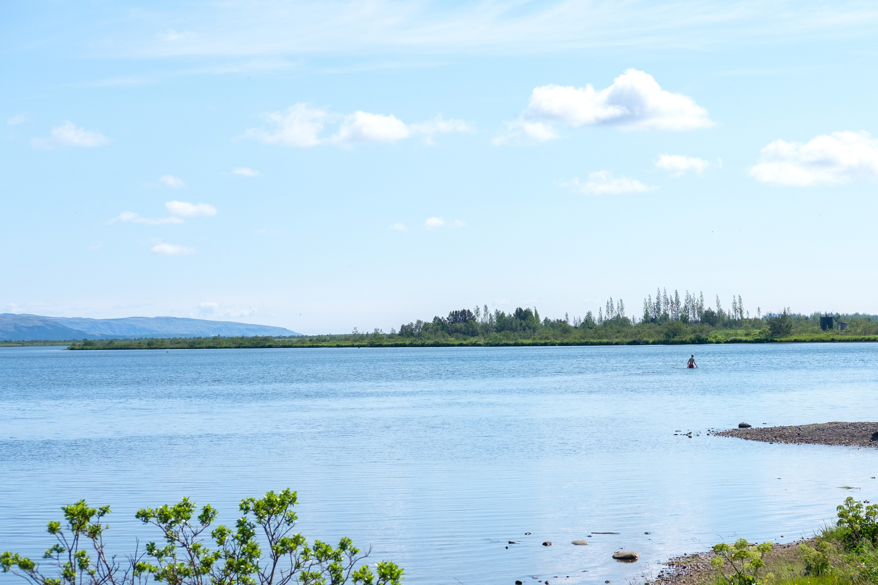 A person wades through Laugarvatn lake in the distance.