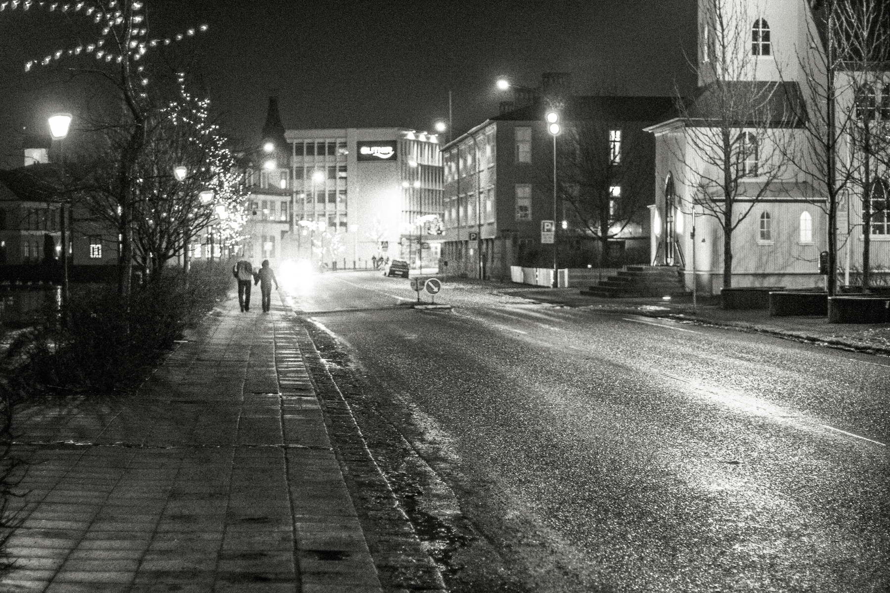 A couple walks along the pond in Reykjavík city centre. On their way home after a New Year’s Eve party. Or on their way to a late party.