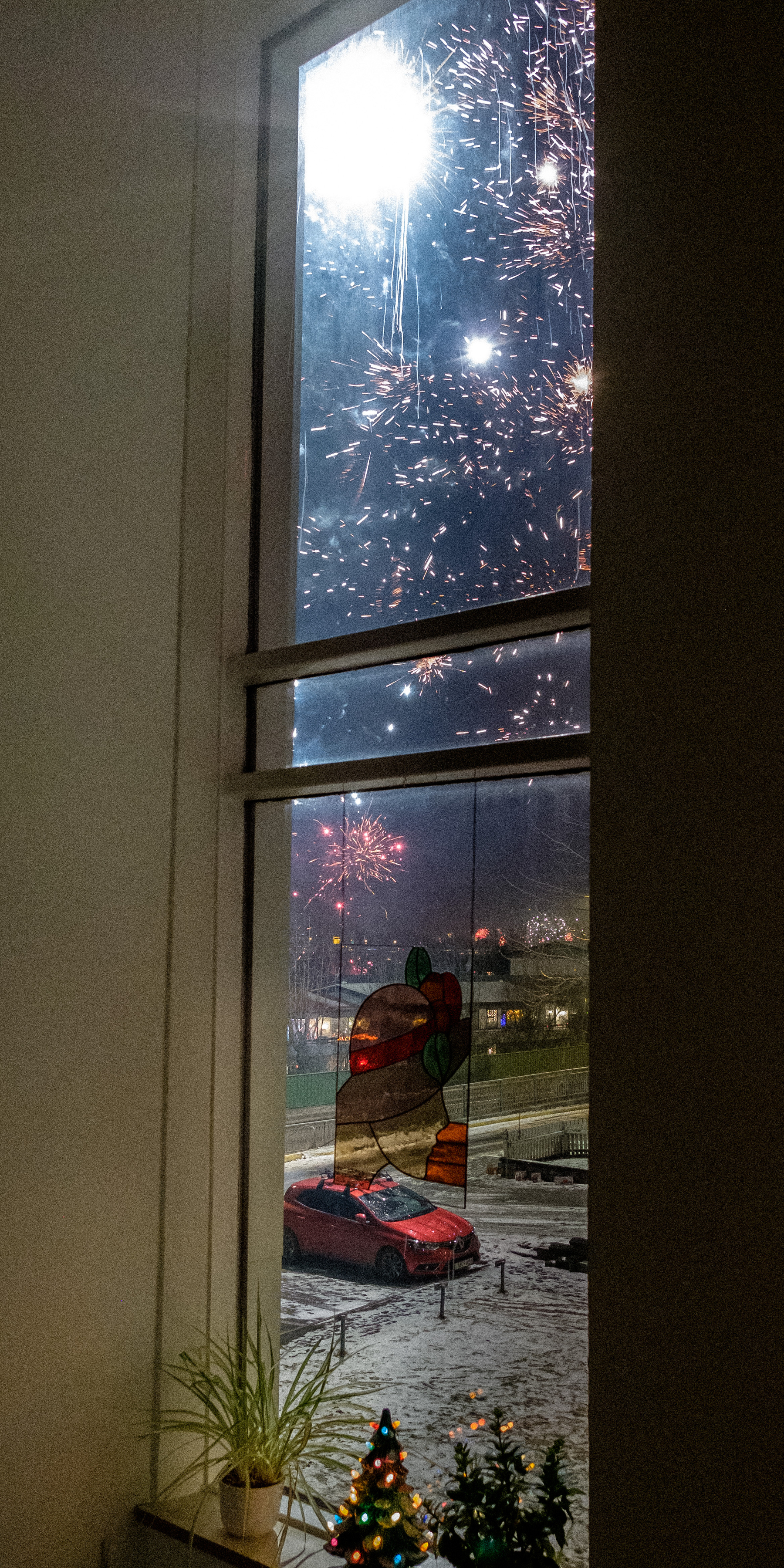 We can see fireworks through a tall window.