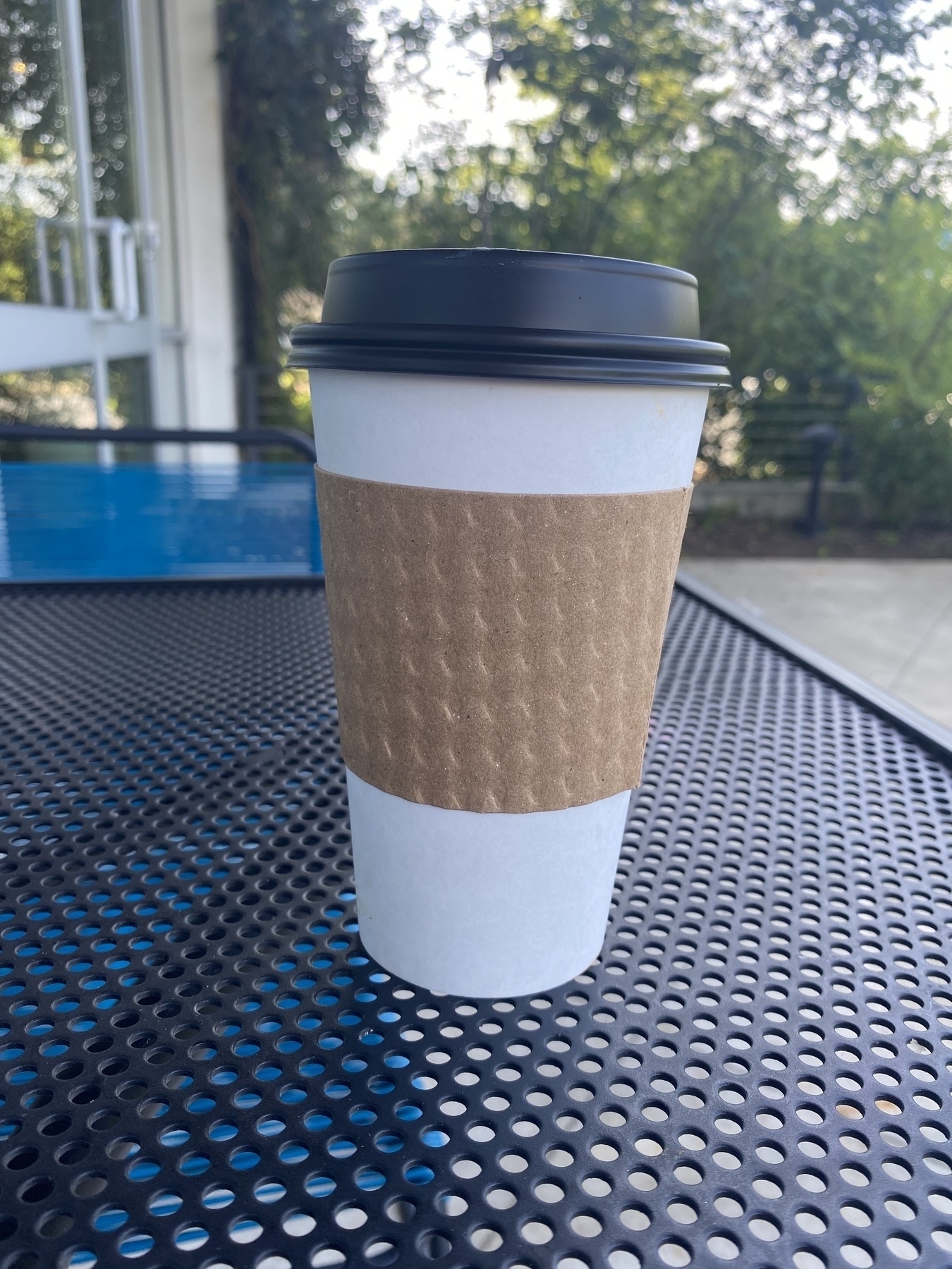Picture of a to-go coffee cup on an outdoor table at Grit Coffee.