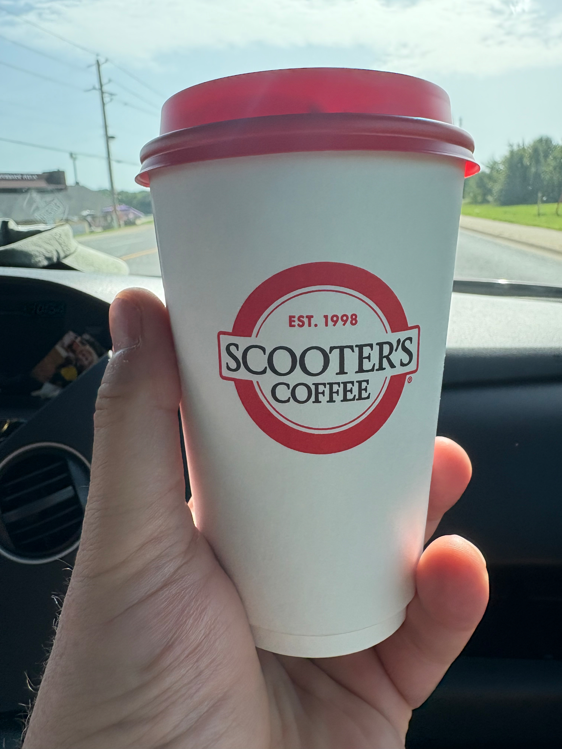 A red and white coffee cup with the Scooter’s Coffee logo on it.