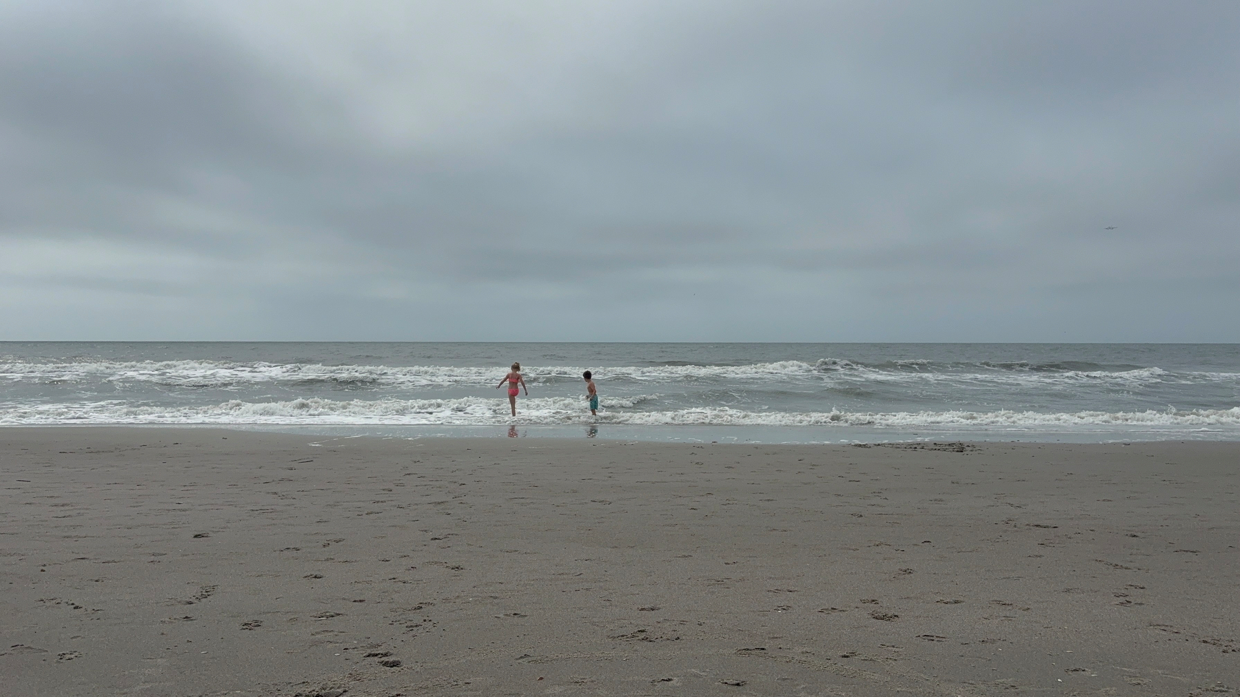Picture of the beach with two kids in the water.