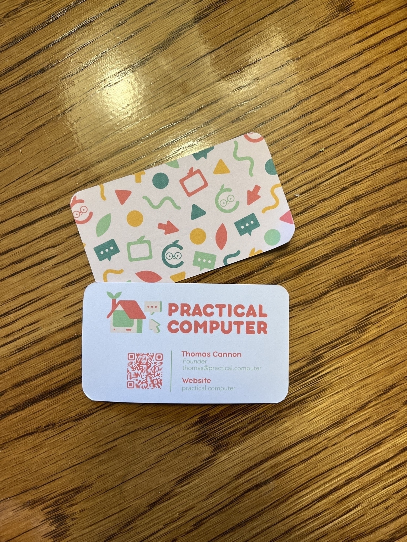A photo of my business card, front & back, which says the name of my business (Practical Computer), my contact information, and has a QR code