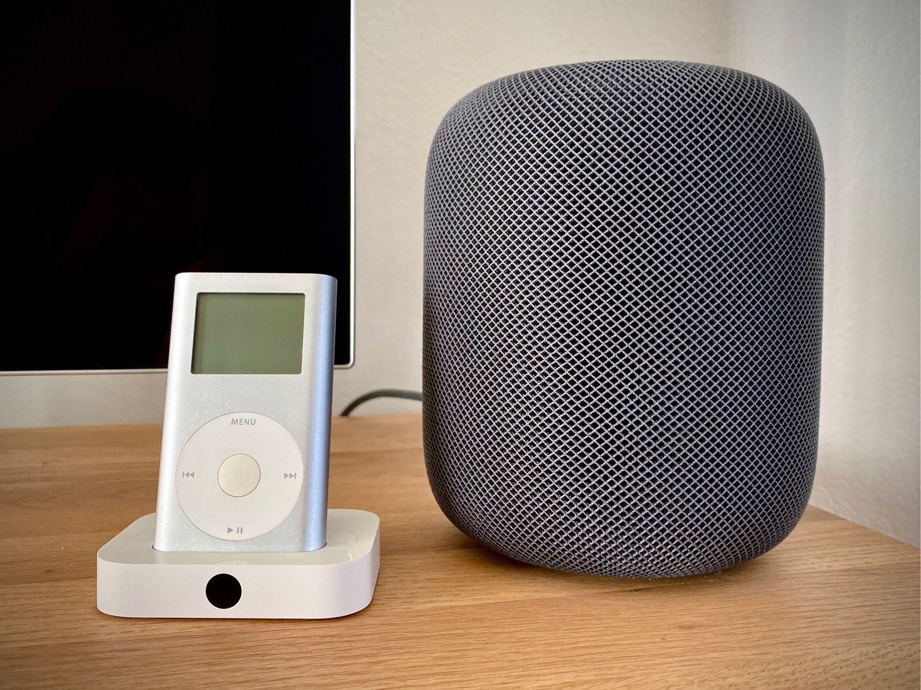 A silver iPod mini in an Apple Universal Dock sits next to a HomePod in space grey.