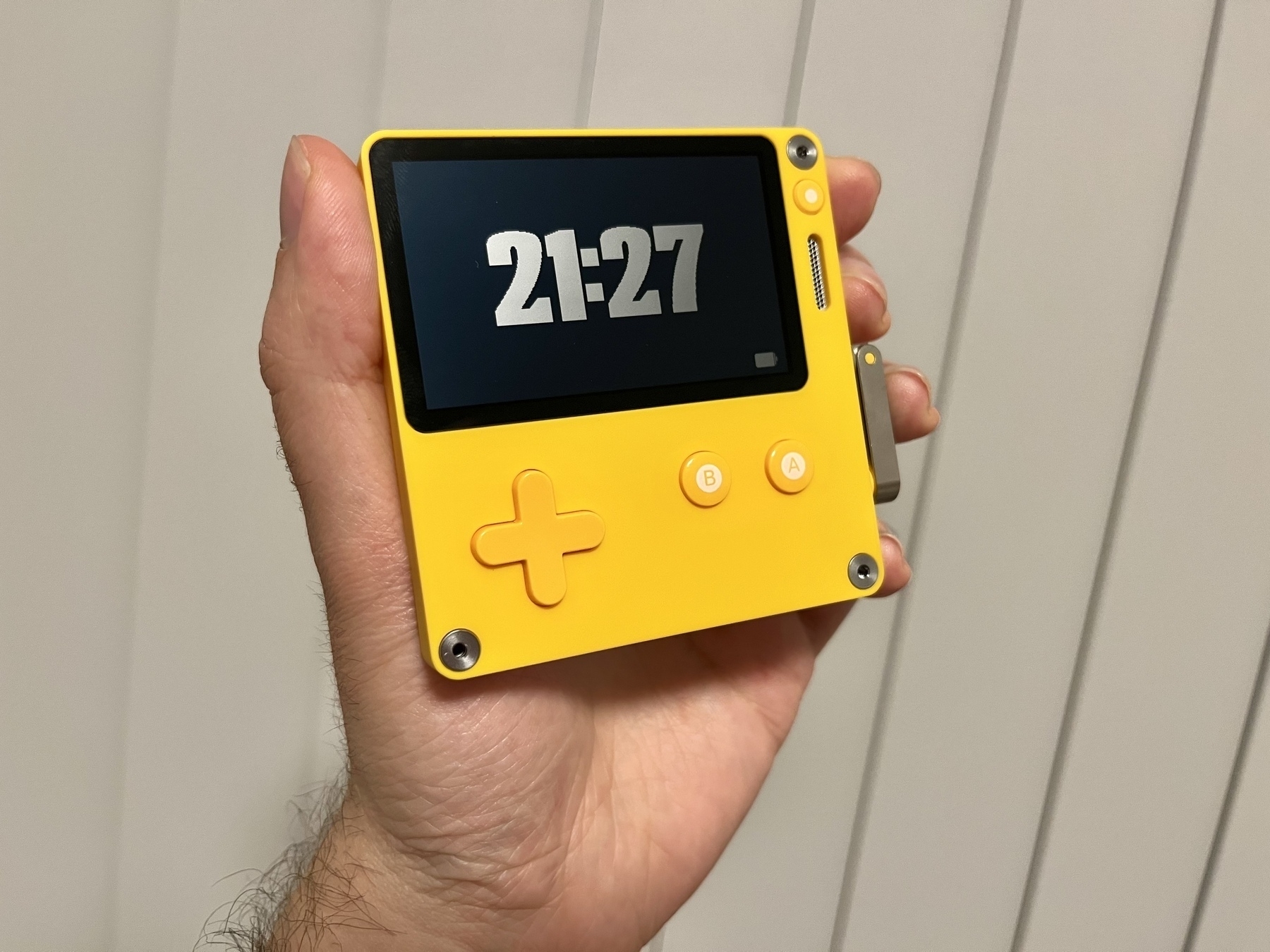 A small, yellow gaming device with a crank