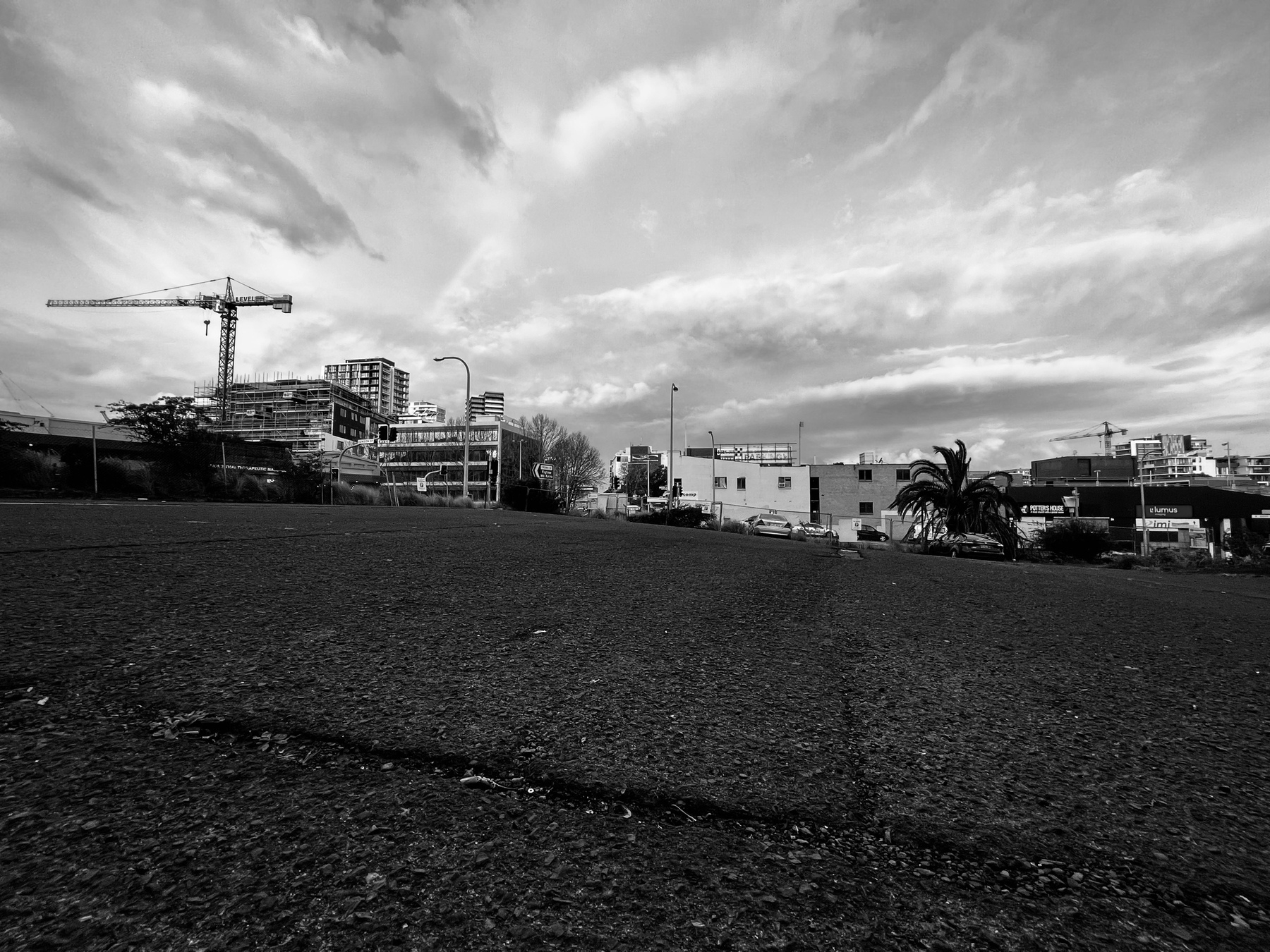 A wide-angle shot that shows a rough road surface in the lower half of the picture and buildings, a crane and the sky in the distance
