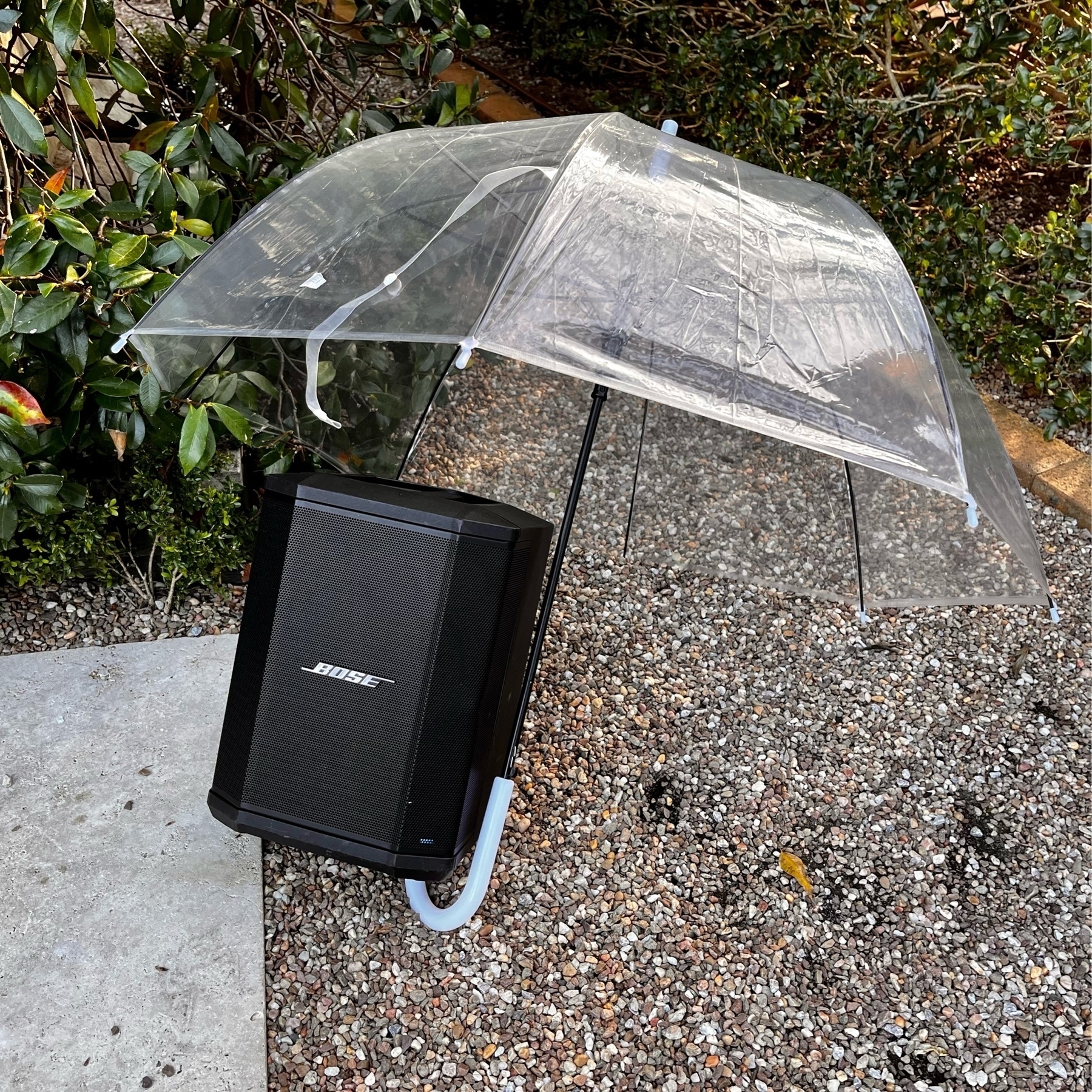 An umbrella propped up over a Bose speaker outside