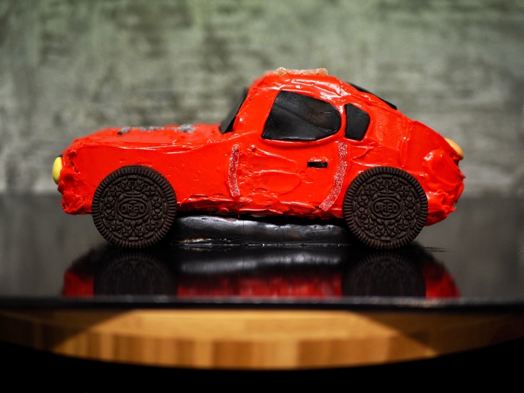 A red racing-car cake on a wooden lazy Susan