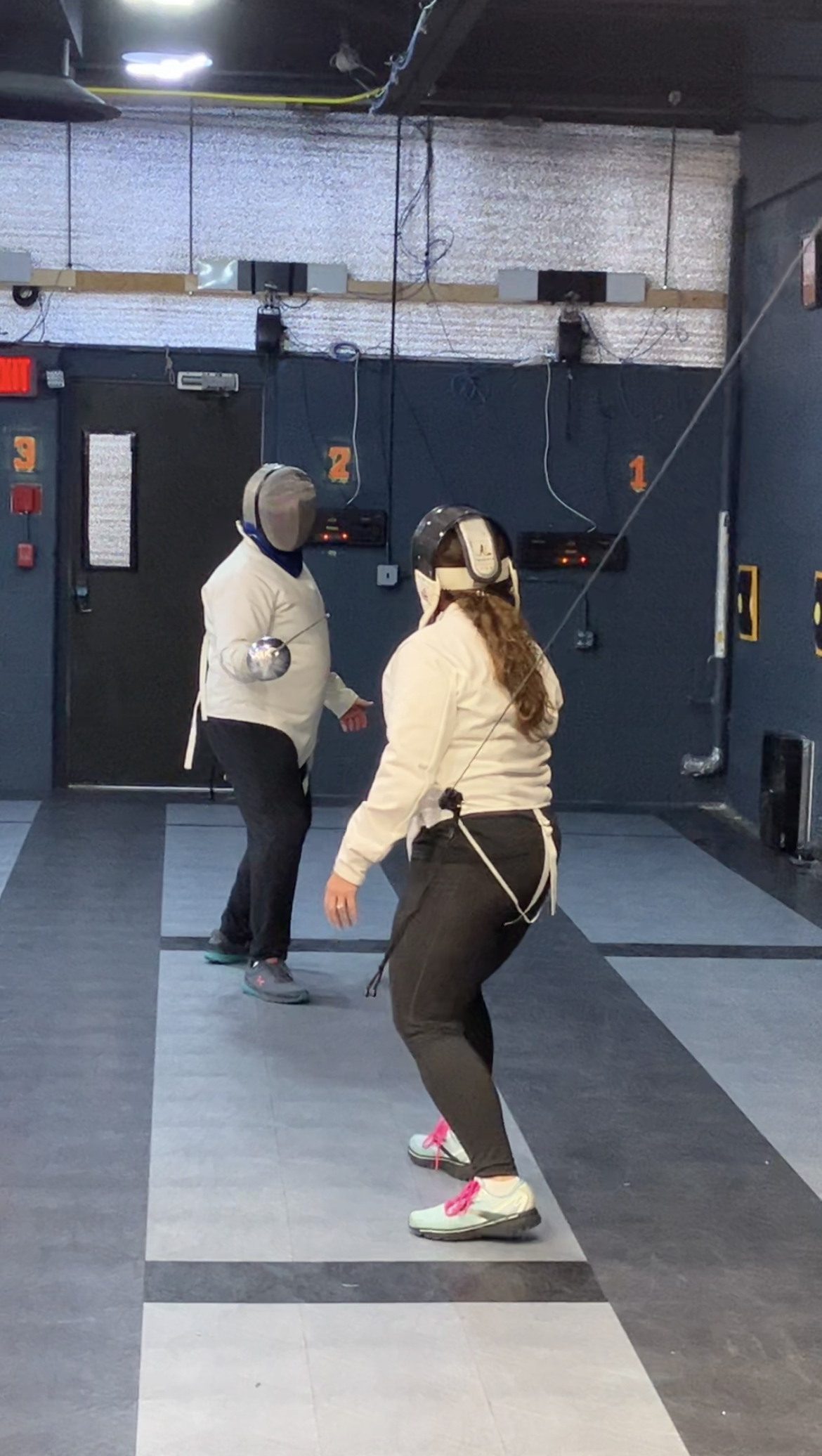 two people fencing in a gym