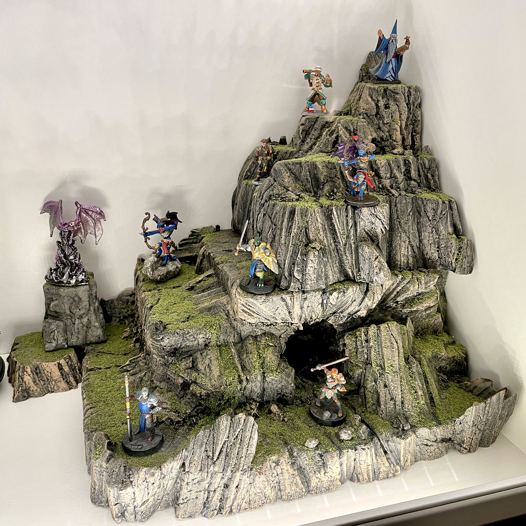 Painted Dungeons and Dragons figures standing on a handmade mountain model