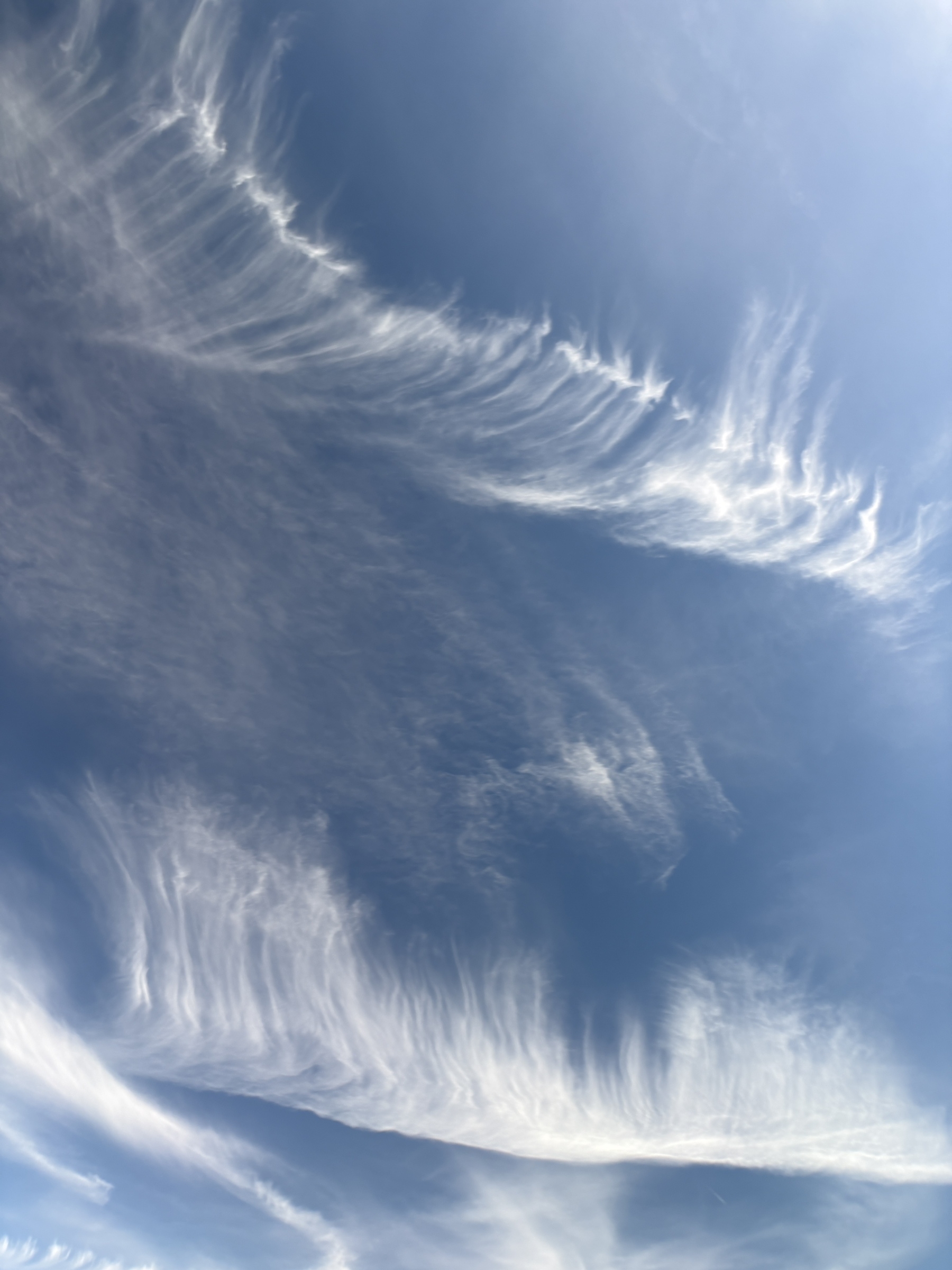Auto-generated description: Wispy white clouds stretch across a bright blue sky, creating a serene and airy scene.