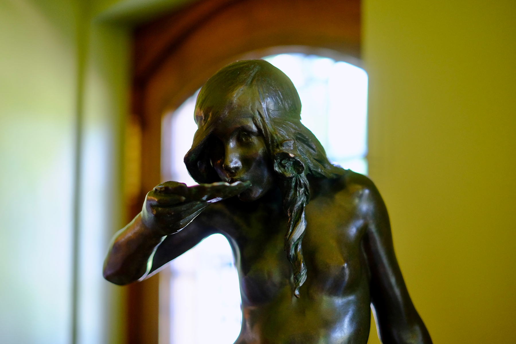 A bronze statue of a girl with long hair drinking from a shell