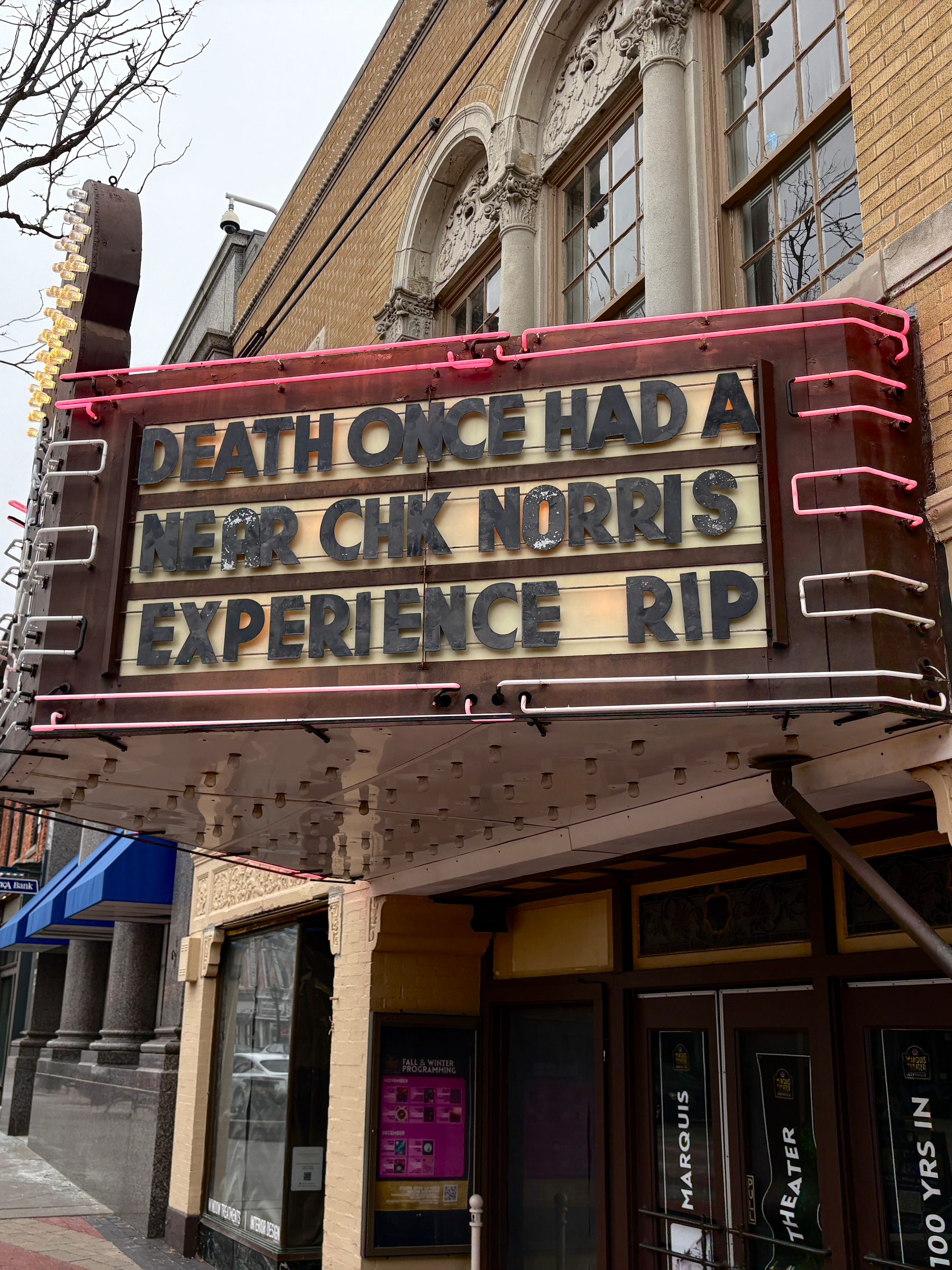 A theater marquee displays a humorous message referencing Death and Chuck Norris.