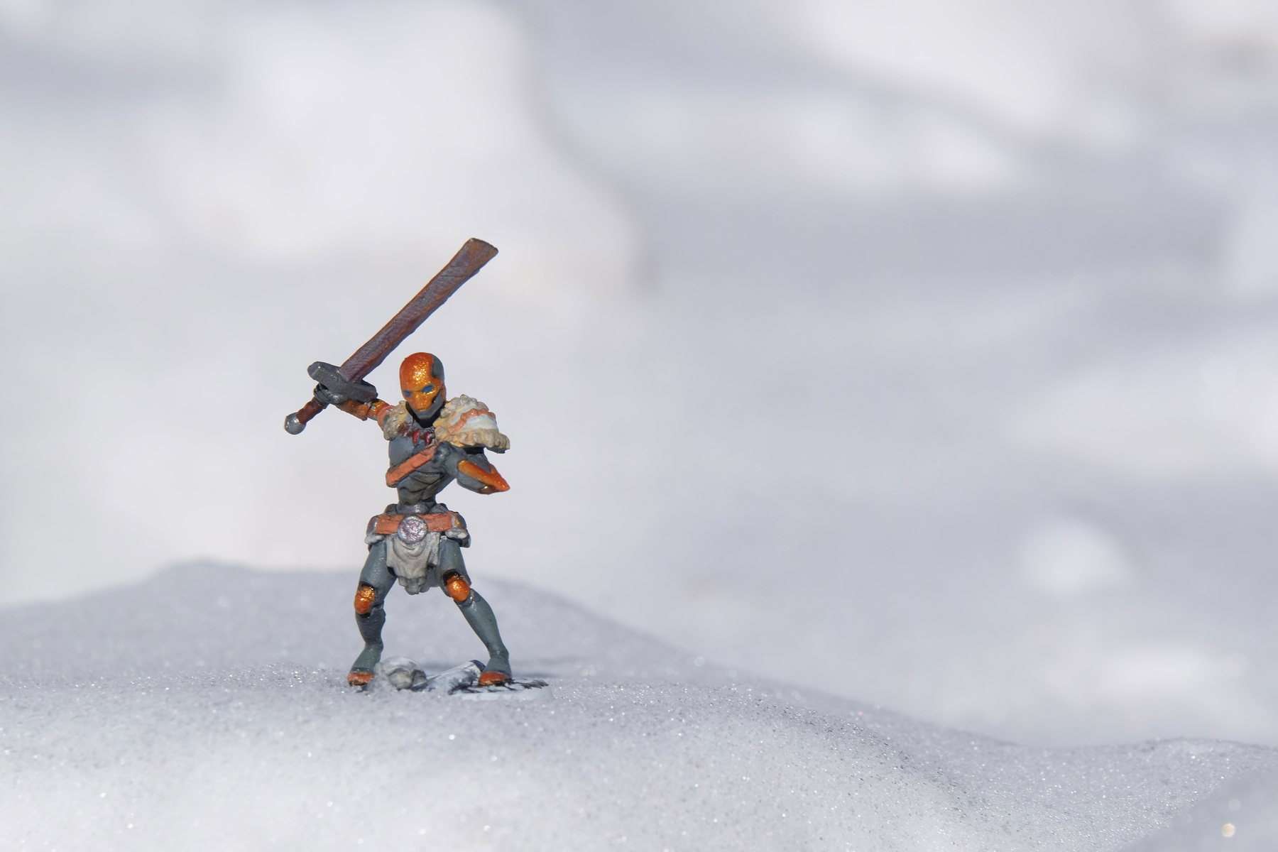 A dungeons and dragons miniature of a warforged holding a sword, stands on a snowy surface.