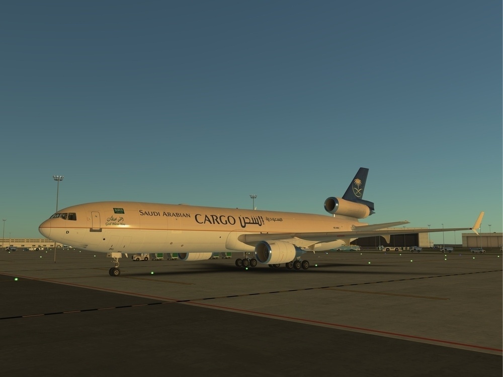 A Saudi Arabian Cargo airplane is parked on an airport tarmac during twilight.