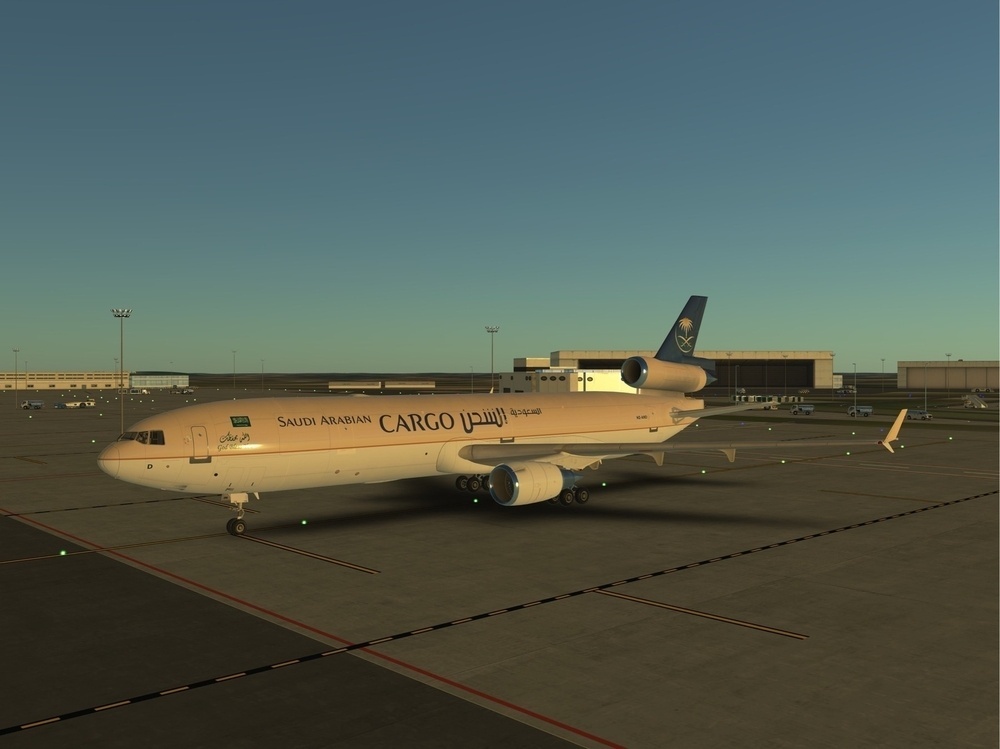 A Saudi Arabian Cargo plane is parked on an airport tarmac at sunset.