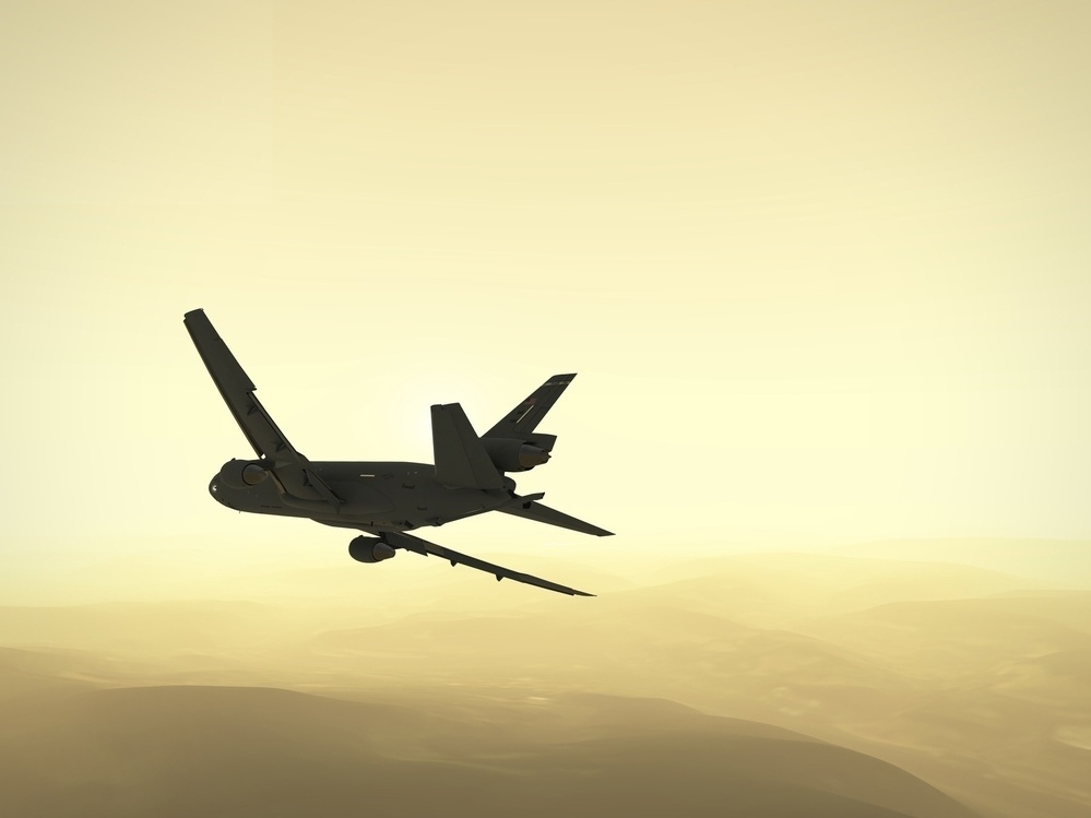 A silhouette of an airplane flies over a hazy, mountainous landscape in a sepia-toned sky.