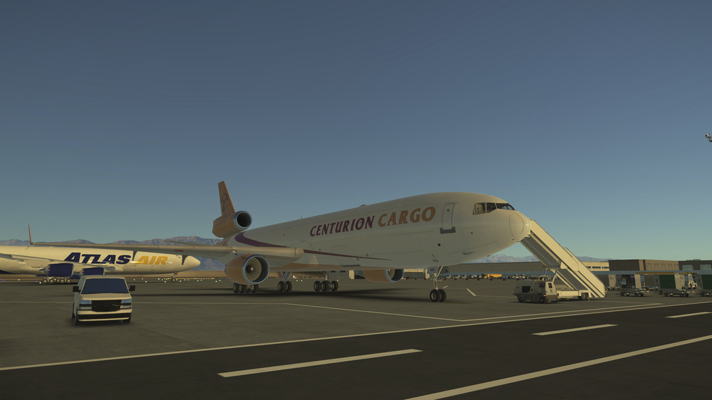 A Centurion Cargo airplane is parked on an airport tarmac with a mobile staircase connected and another Atlas Air plane visible in the background.