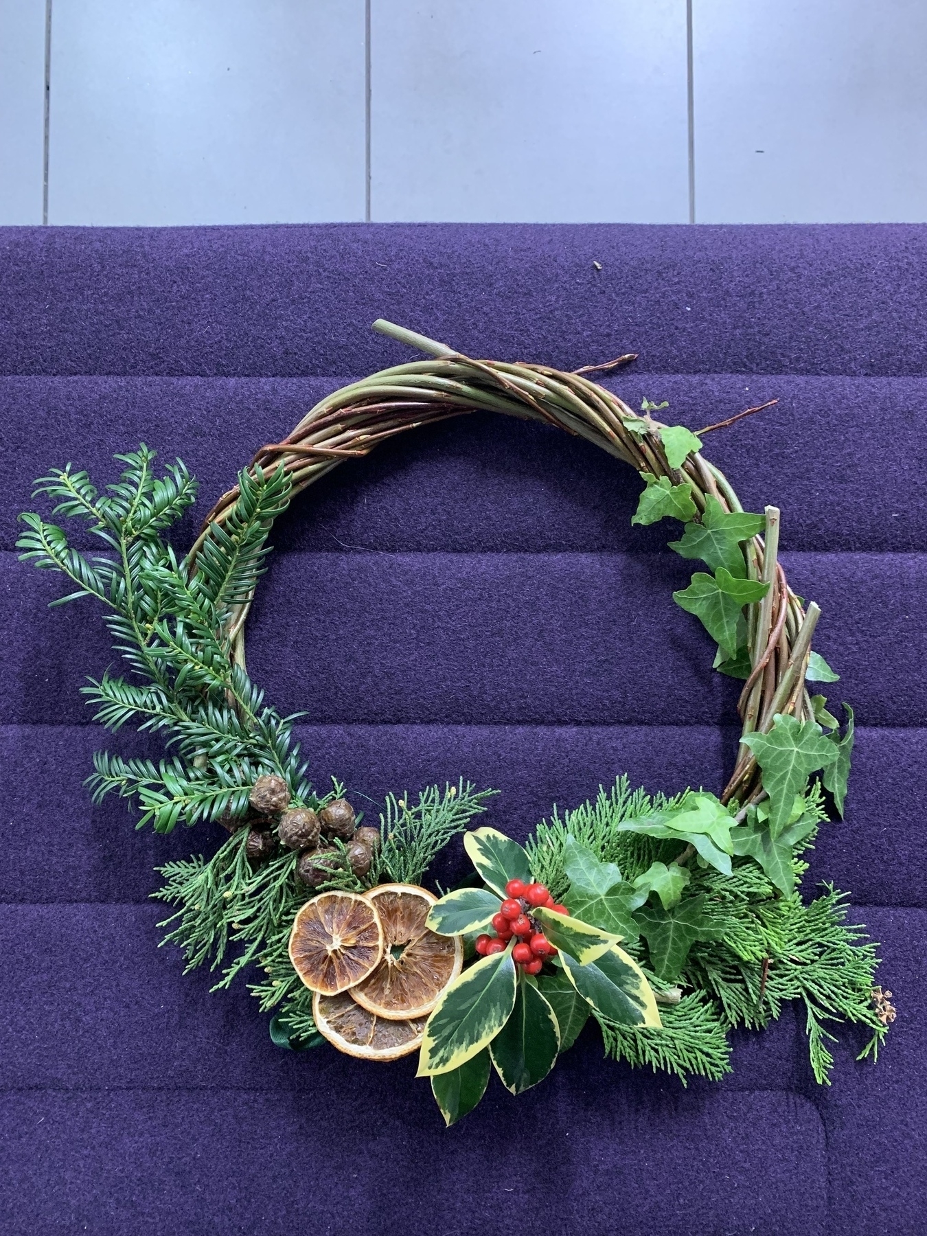 Woven willow hoop with evergreen and ivy decorations.