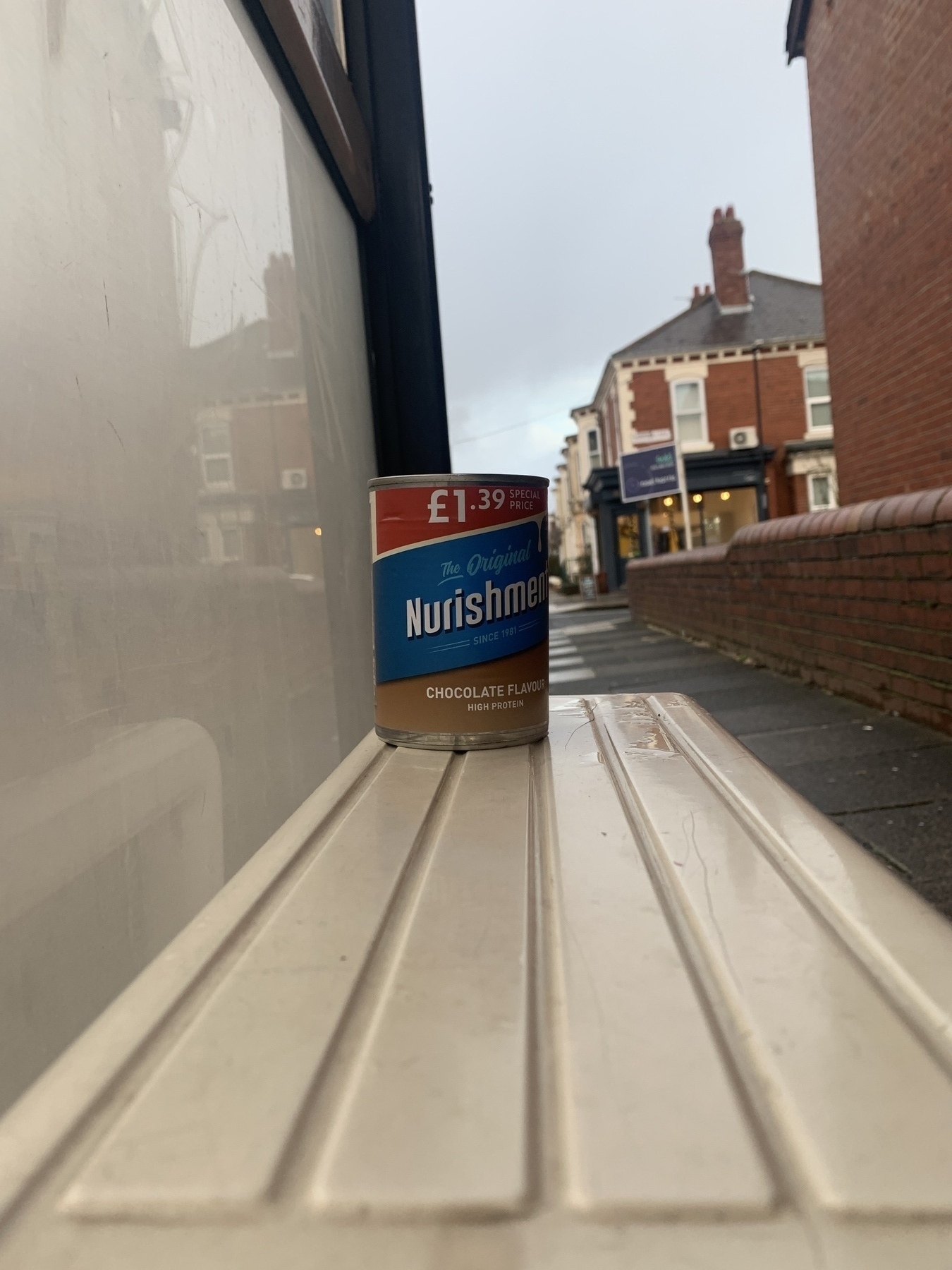 An open can of The Original Nurishment sitting on the bus stop bench.