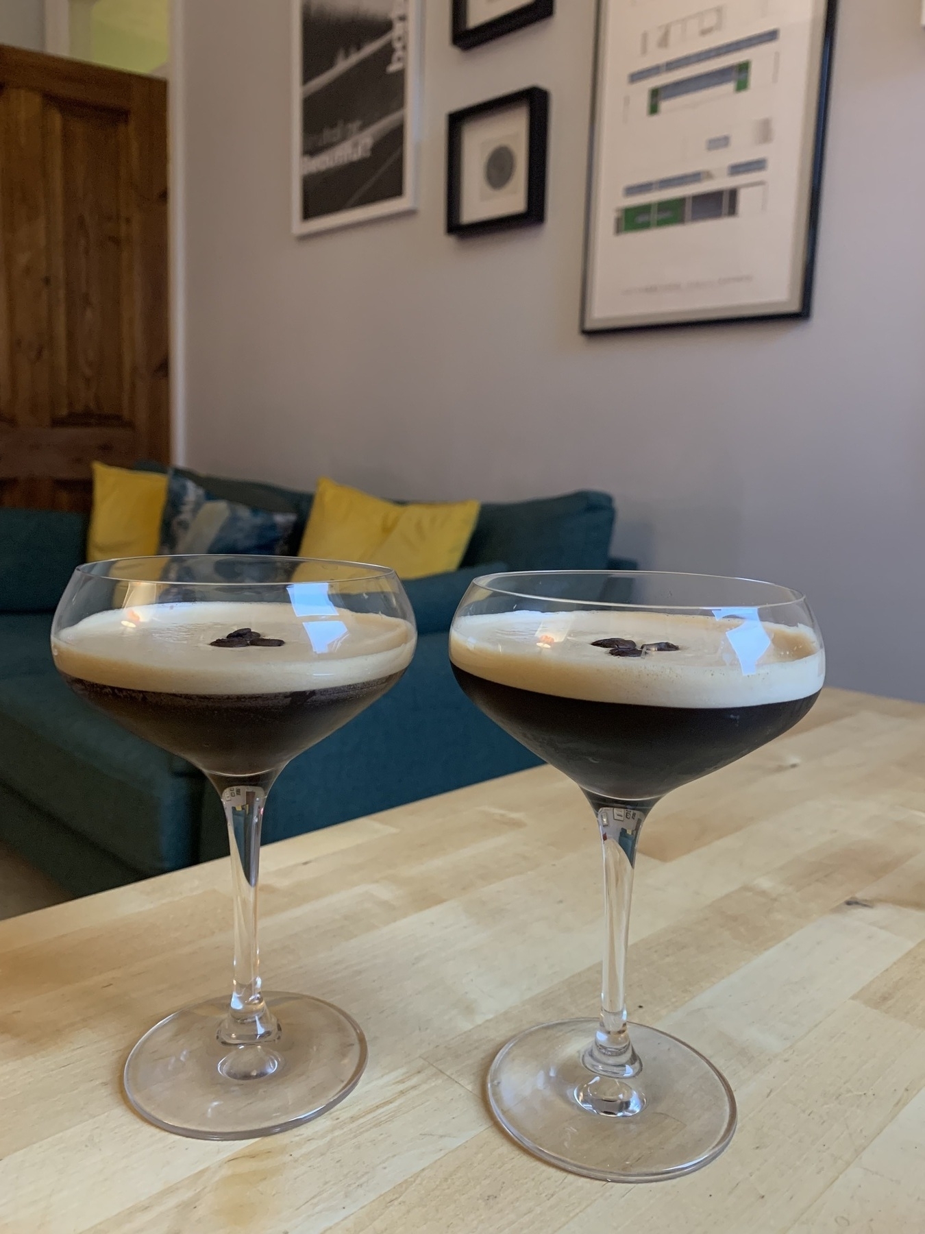 Two espresso martinis on a table in front of a sofa.