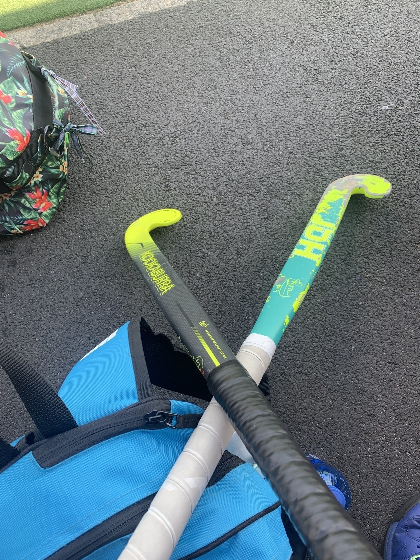 Two crossed field hockey sticks resting on a blue bag at the side of the pitch.