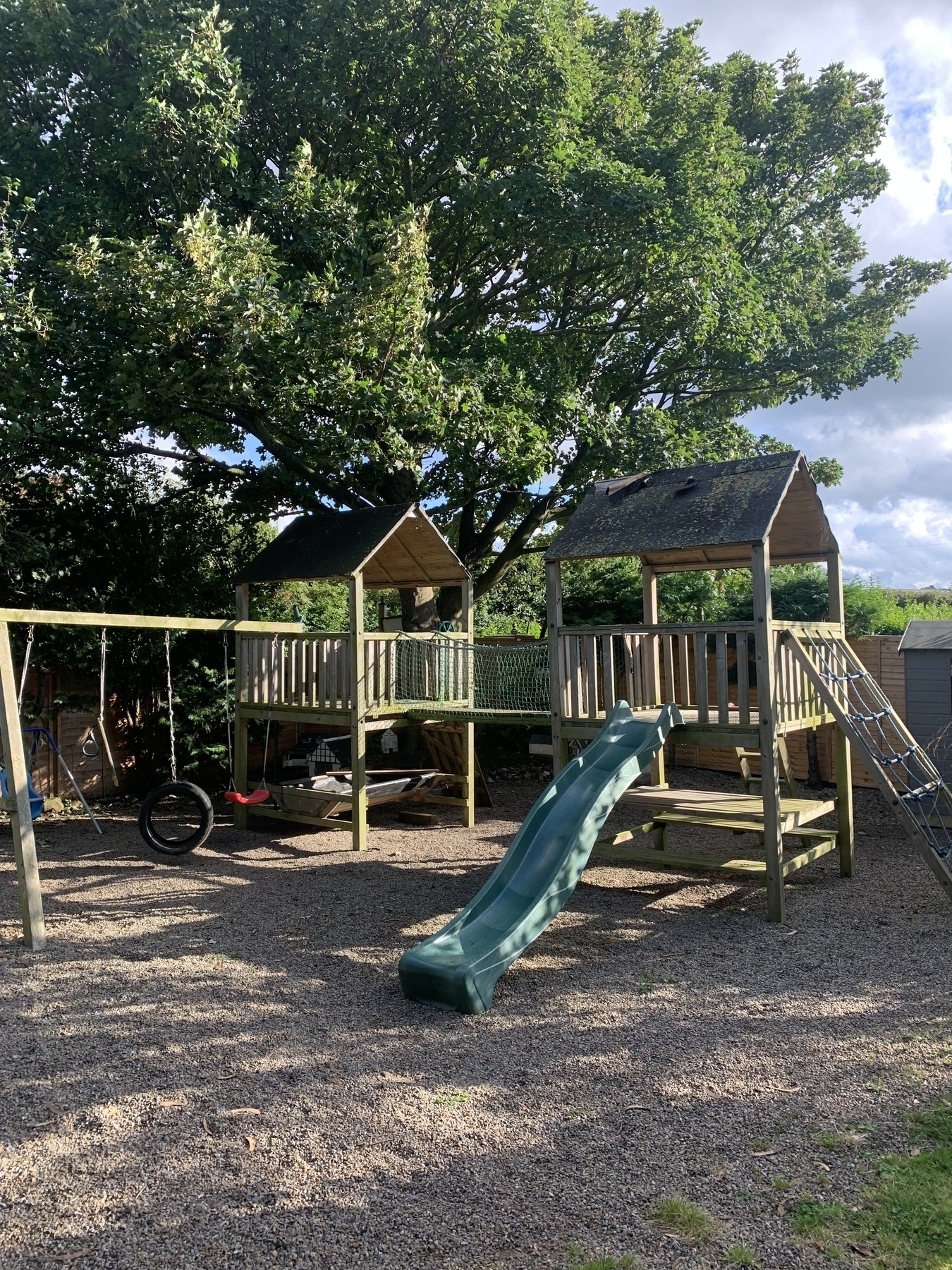 Wooden climbing frame with slide and tyre swing.