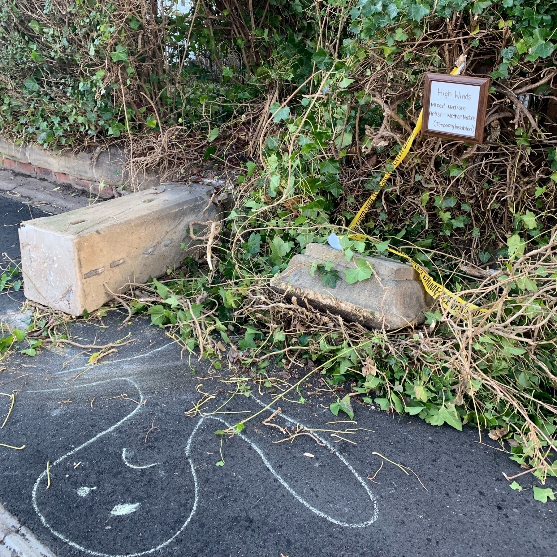 Stone gate post fallen across pavement. Hand written sign describing scene as art work