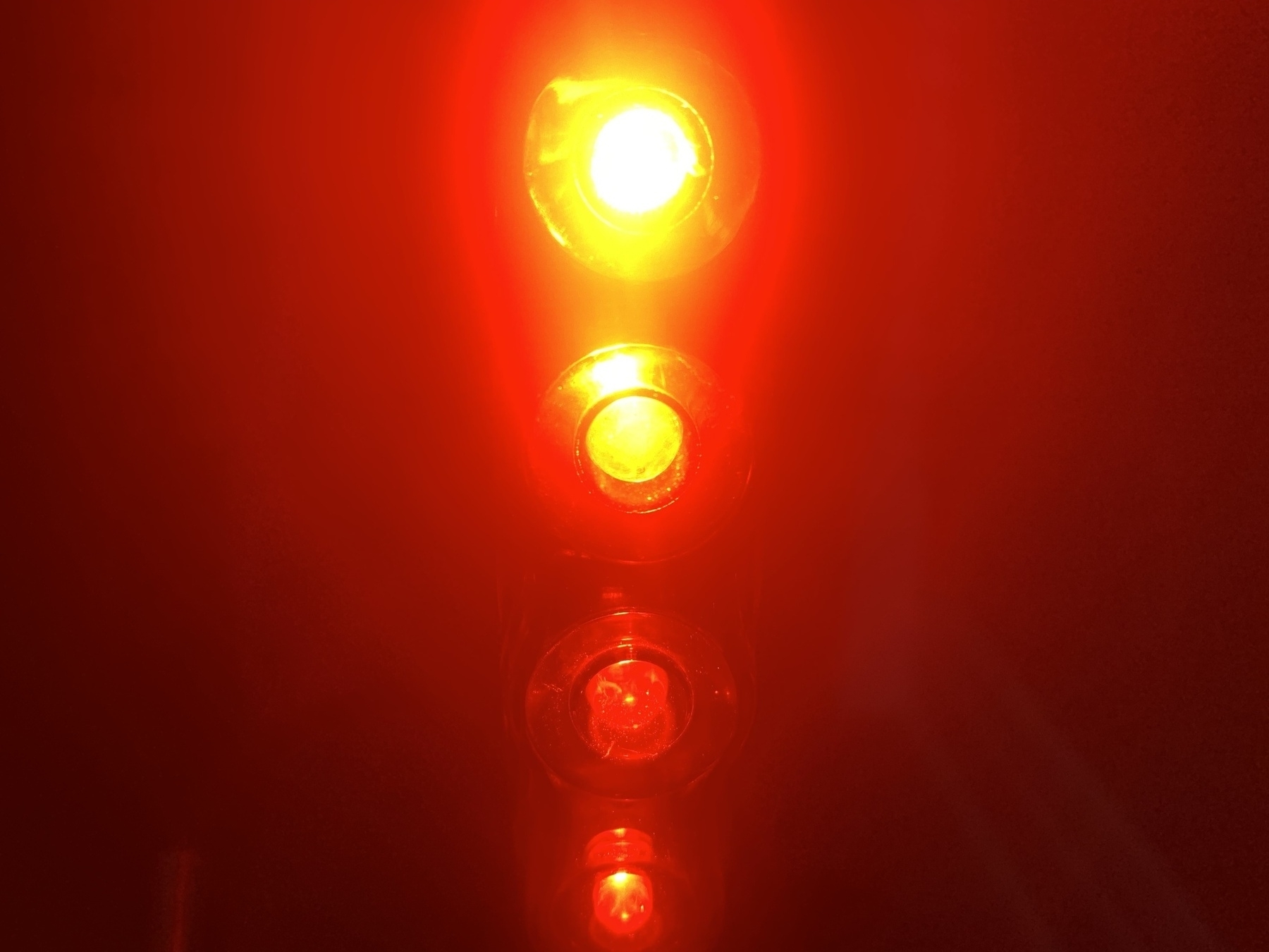 Closeup of rear bike light. Four vertical red bulbs with brightest at the top.