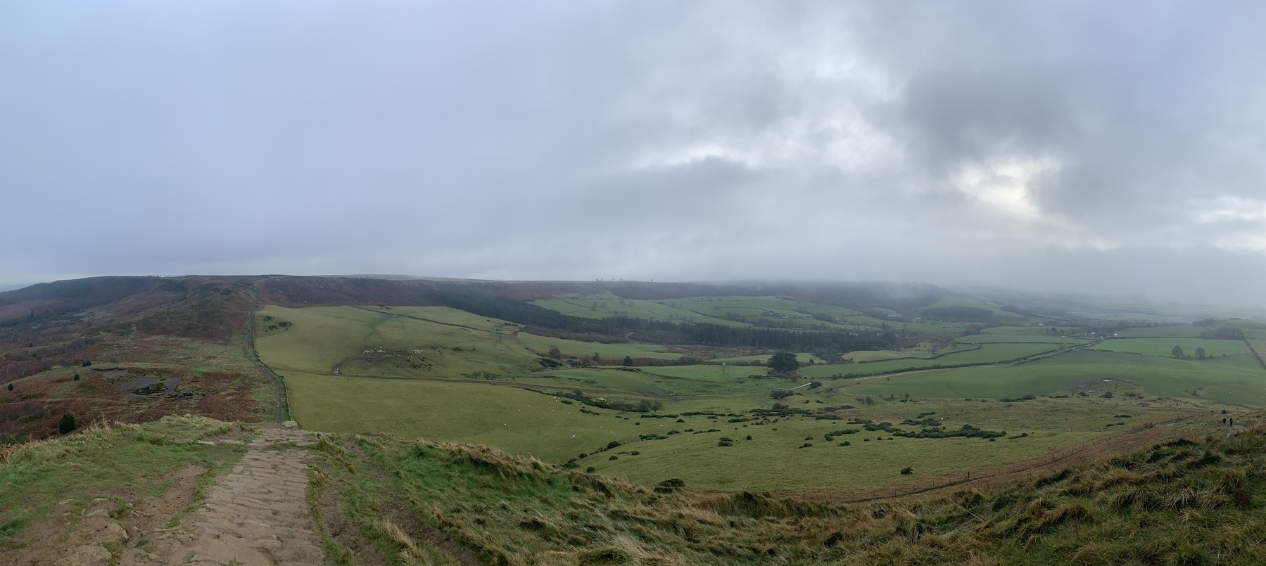 Panoramic view of moor and farmland from part-way up Roseberry Topping on an overcast day.