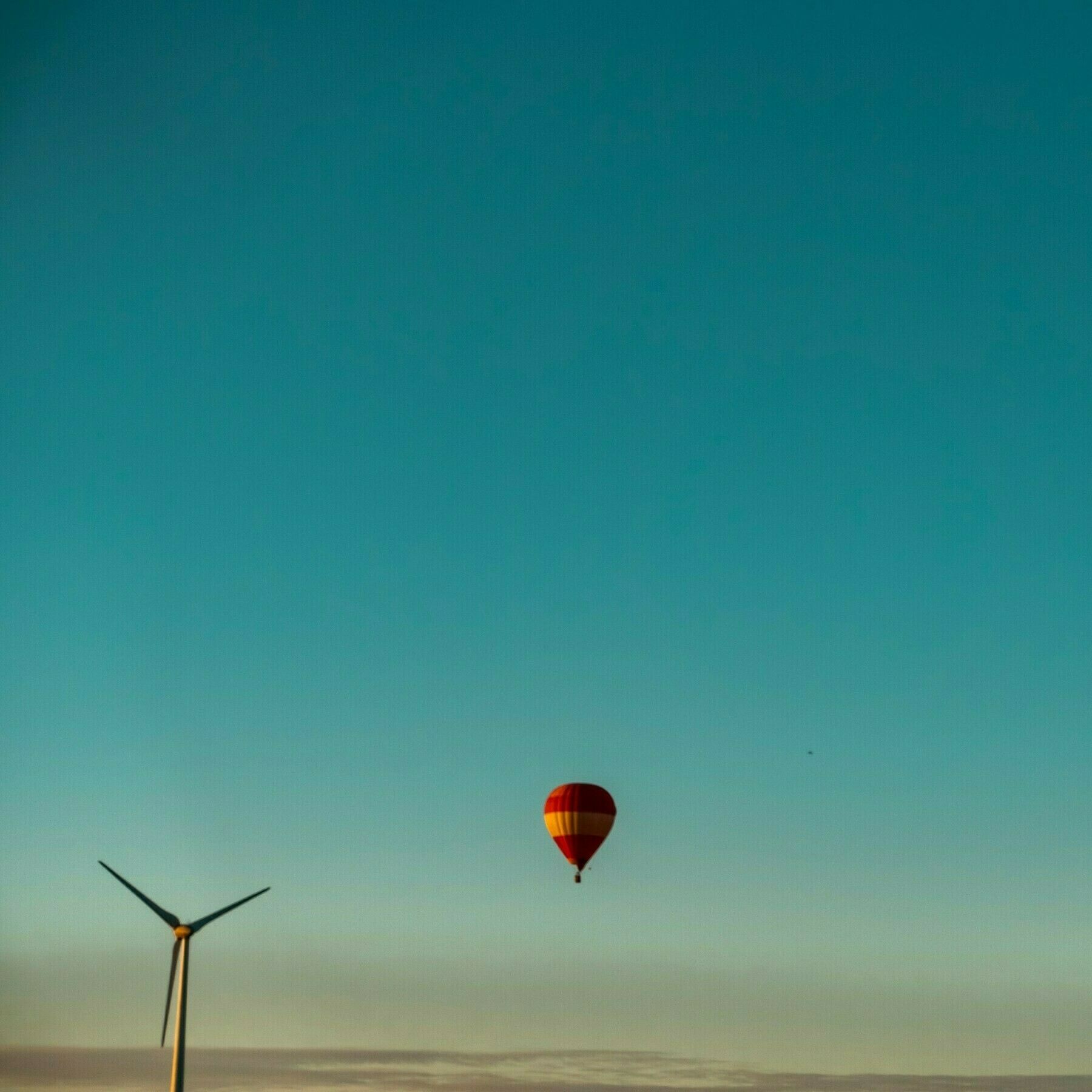 Windmill and a hot air balloon in the sky with a blue sky just before sunset