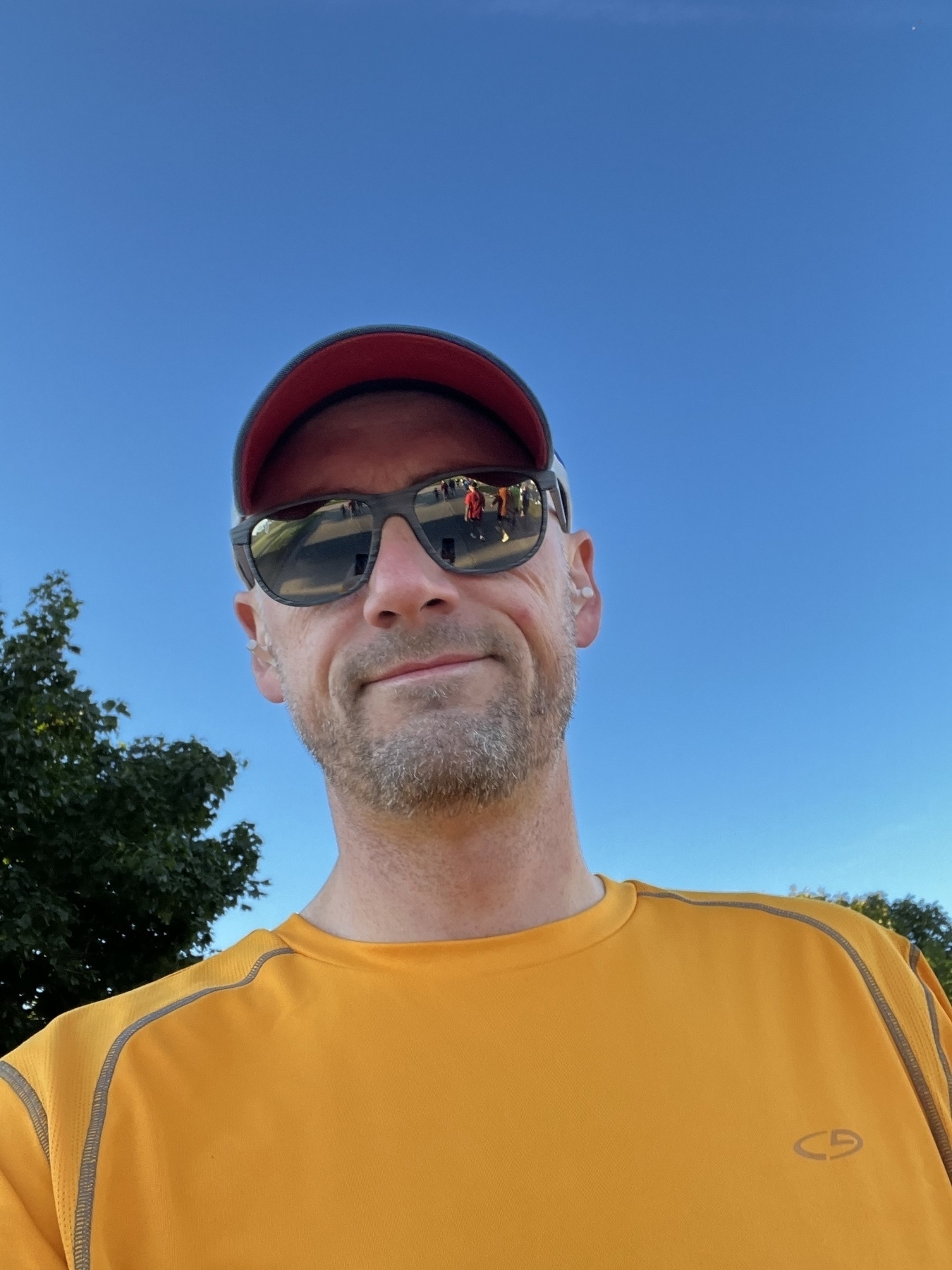 Selfie of a Bearded man in a yellow shirt and sunglasses against a blue sky