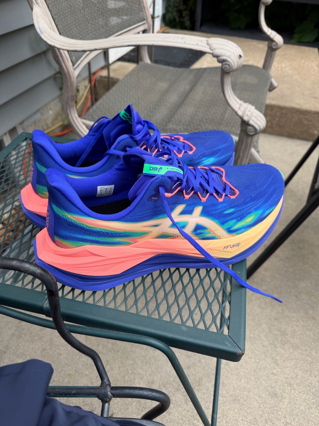 A pair of blue ASICS running shoes sitting on a patio table