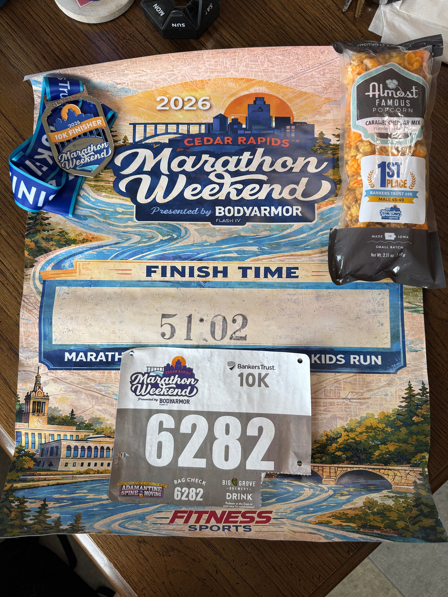 A marathon event kit includes a bib, a medal, a snack pack, and a decorative finisher's sign.
