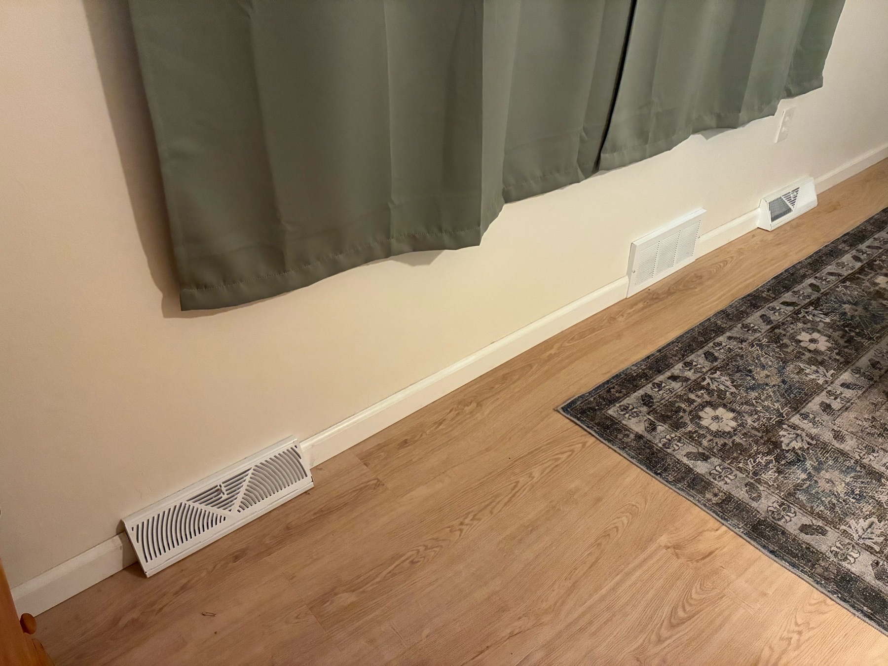 Two baseboard registers, with a cold air return register in the middle.