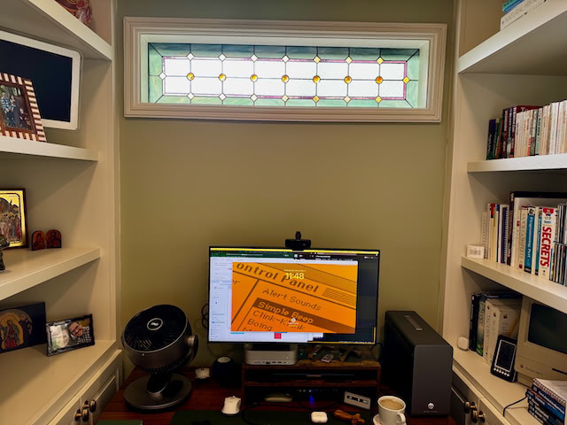 Standing desk with a stained glass windows behind it.  Two bookshelves on either side.