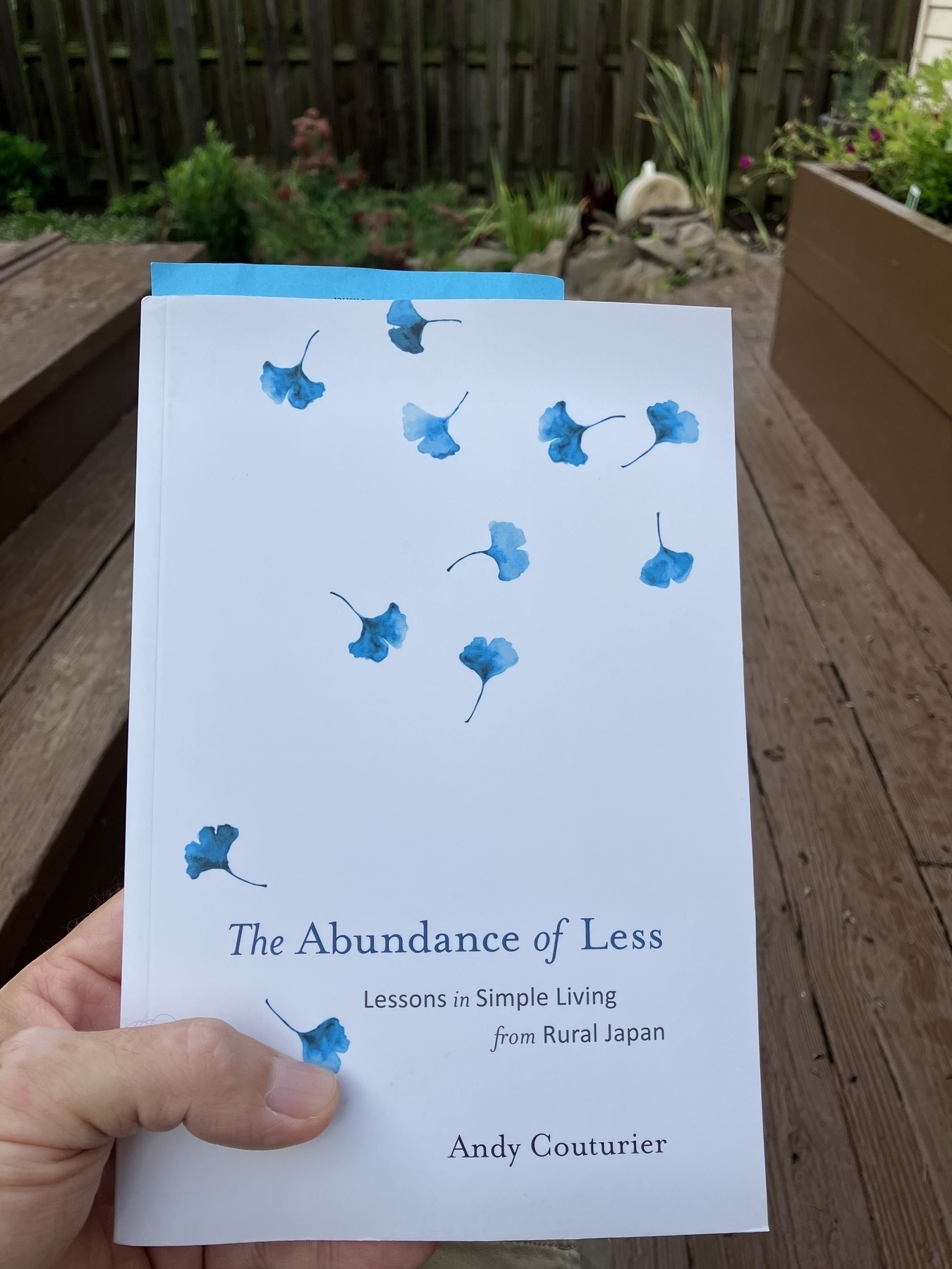 Cover of book titled The Abundance of Less with garden in the background.