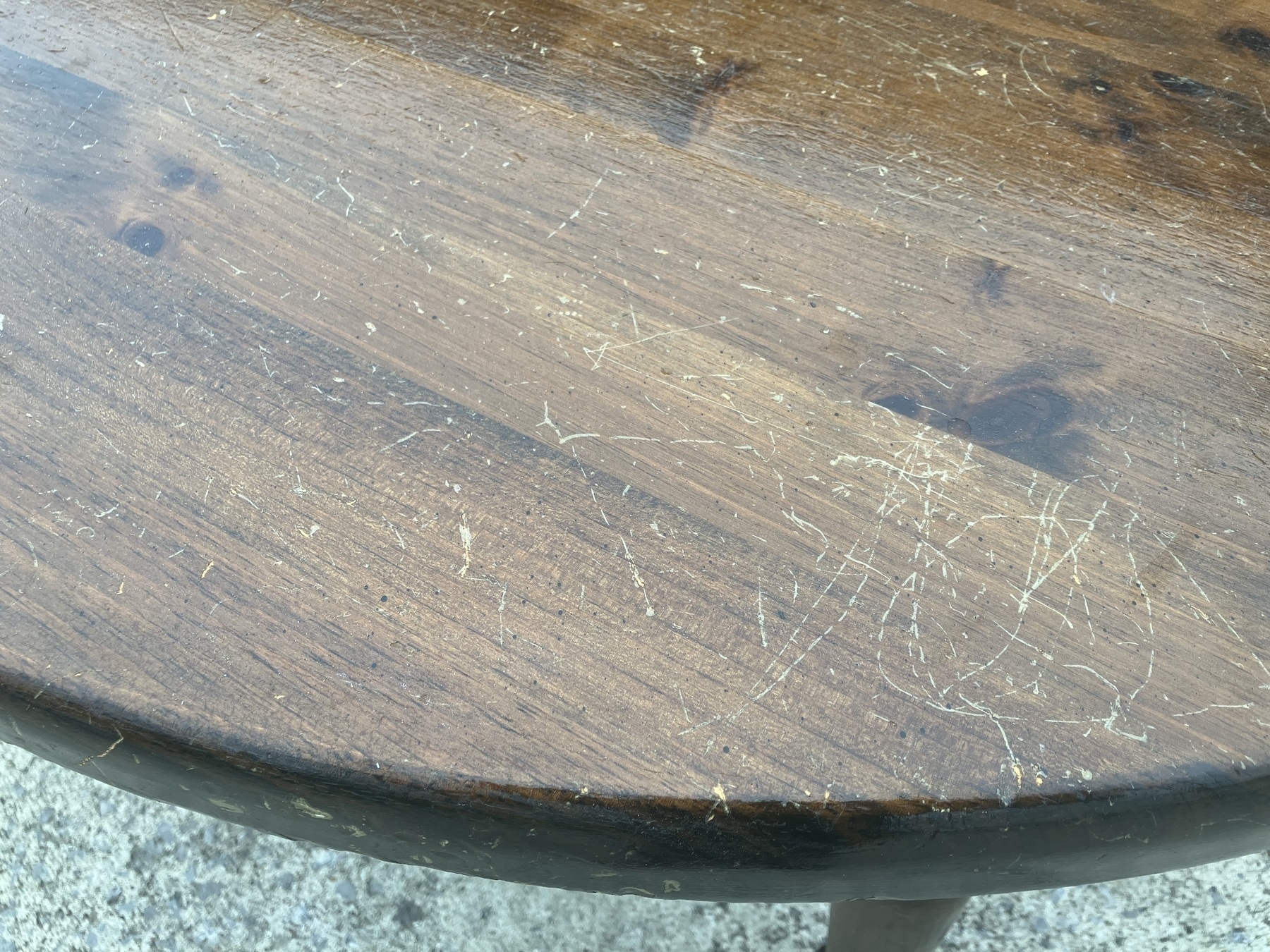 Auto-generated description: A wooden tabletop is scratched and worn, showing signs of heavy use.