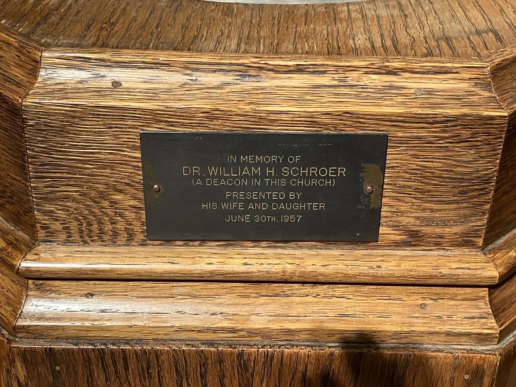 Auto-generated description: A wooden surface features a plaque dedicated to Dr. William H. Schroer, presented by his wife and daughter on June 30th, 1957.