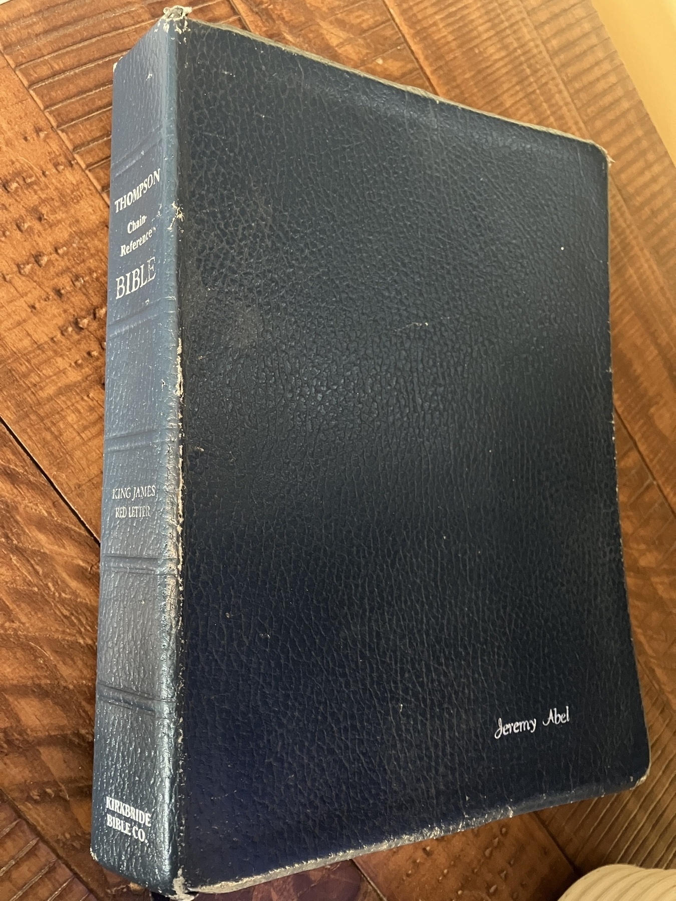 Auto-generated description: A black leather-bound King James Bible lies on a wooden surface, displaying the name Jeremy Abel embossed on the cover.