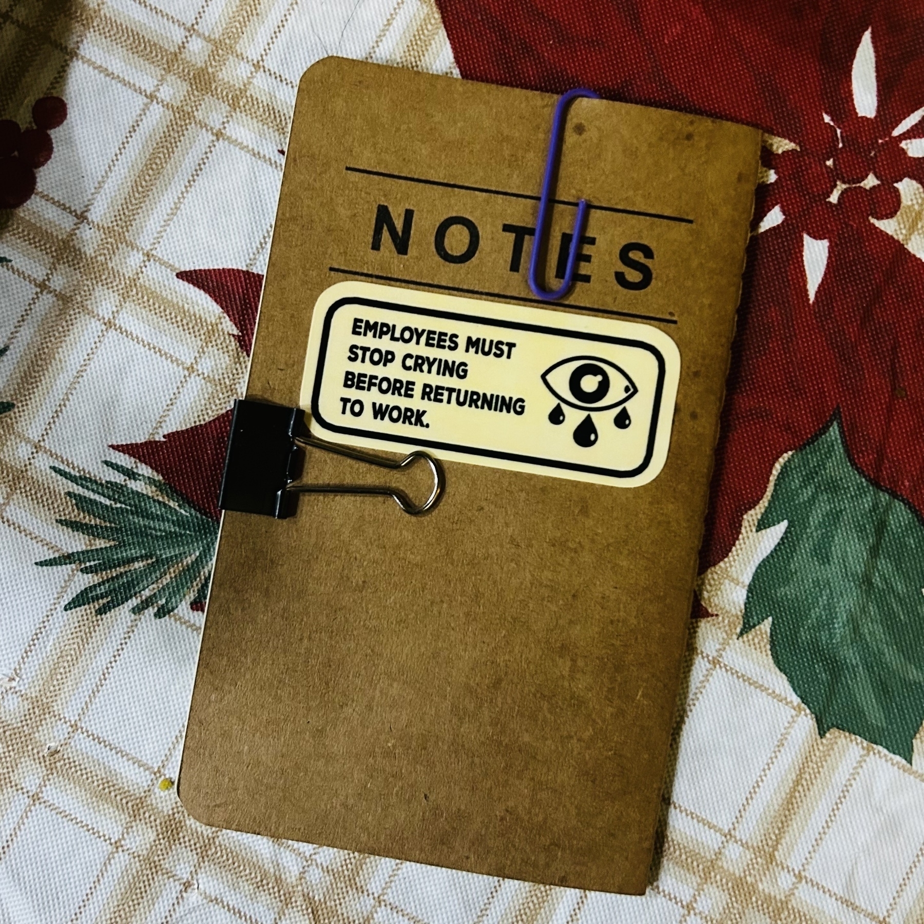 New 3.5-by-5.5-inch brown notebook with sticker on it that says, “Employees must stop crying before returning to work.”