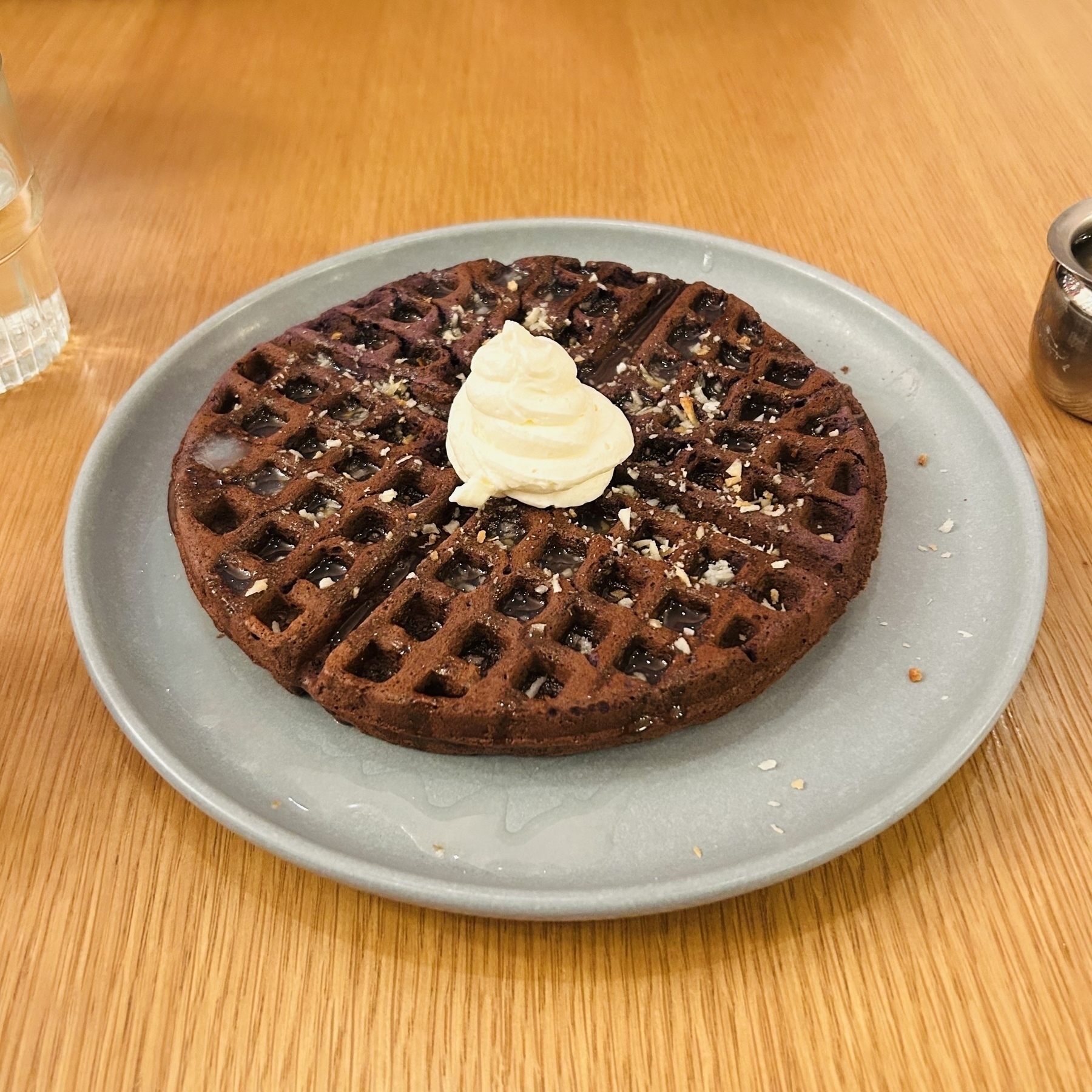 Brownish ube waffle with coconut glaze and a dollop of whipped cream in the middle. 