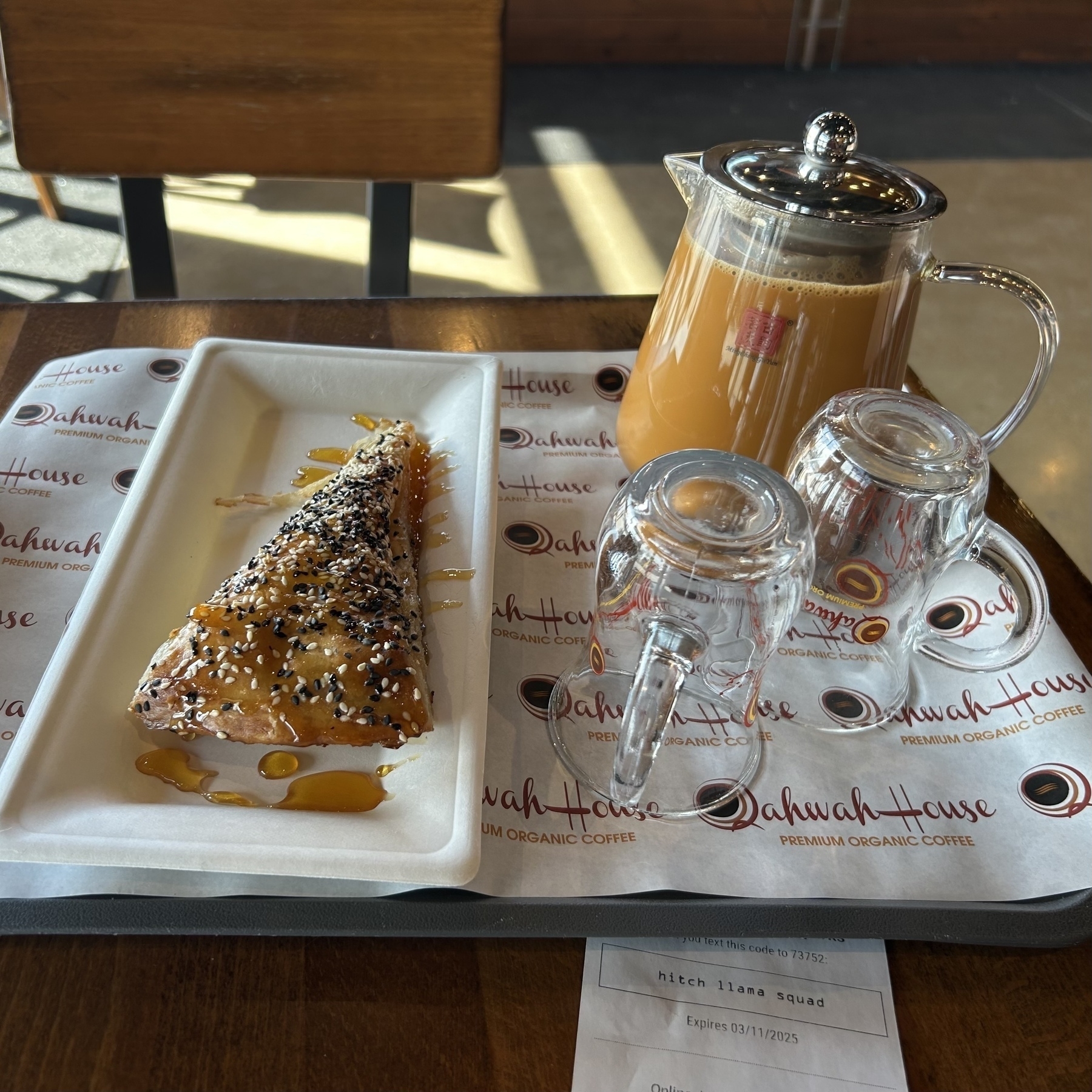 A small pot of Adeni chai with two glasses and a slice of buttery Yemeni sabaya pastry. 