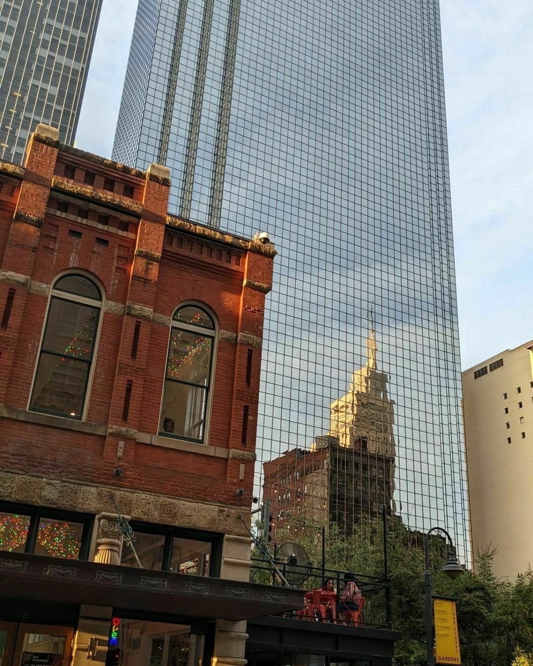 Early 1900s red brick low-story building with a glass-fronted skyscraper behind.