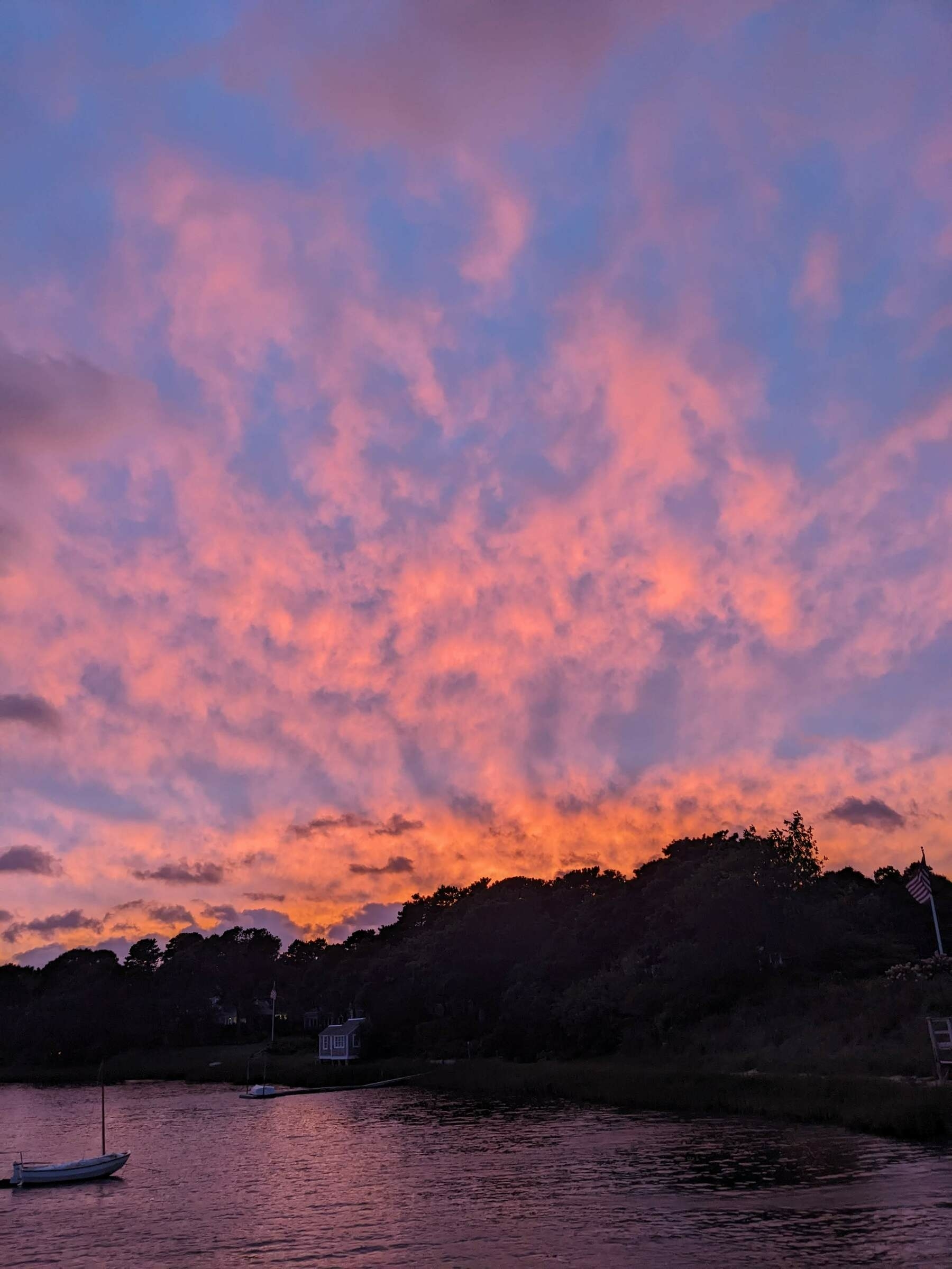 Orangey and blue clouds over a Cape Code inlet at sunset.