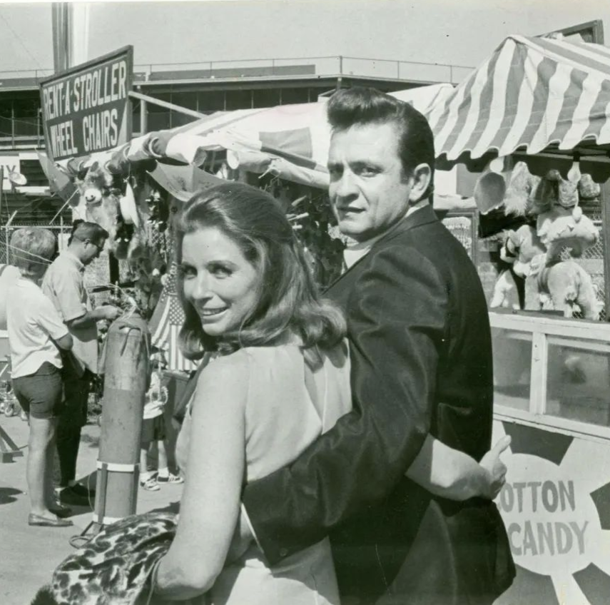 June Carter Cash and Johnny Cash, arm in arm at a fair.