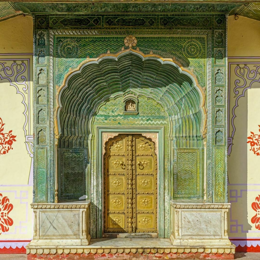 Golden doors surrounded by ornate green plasterwork in an Indian style