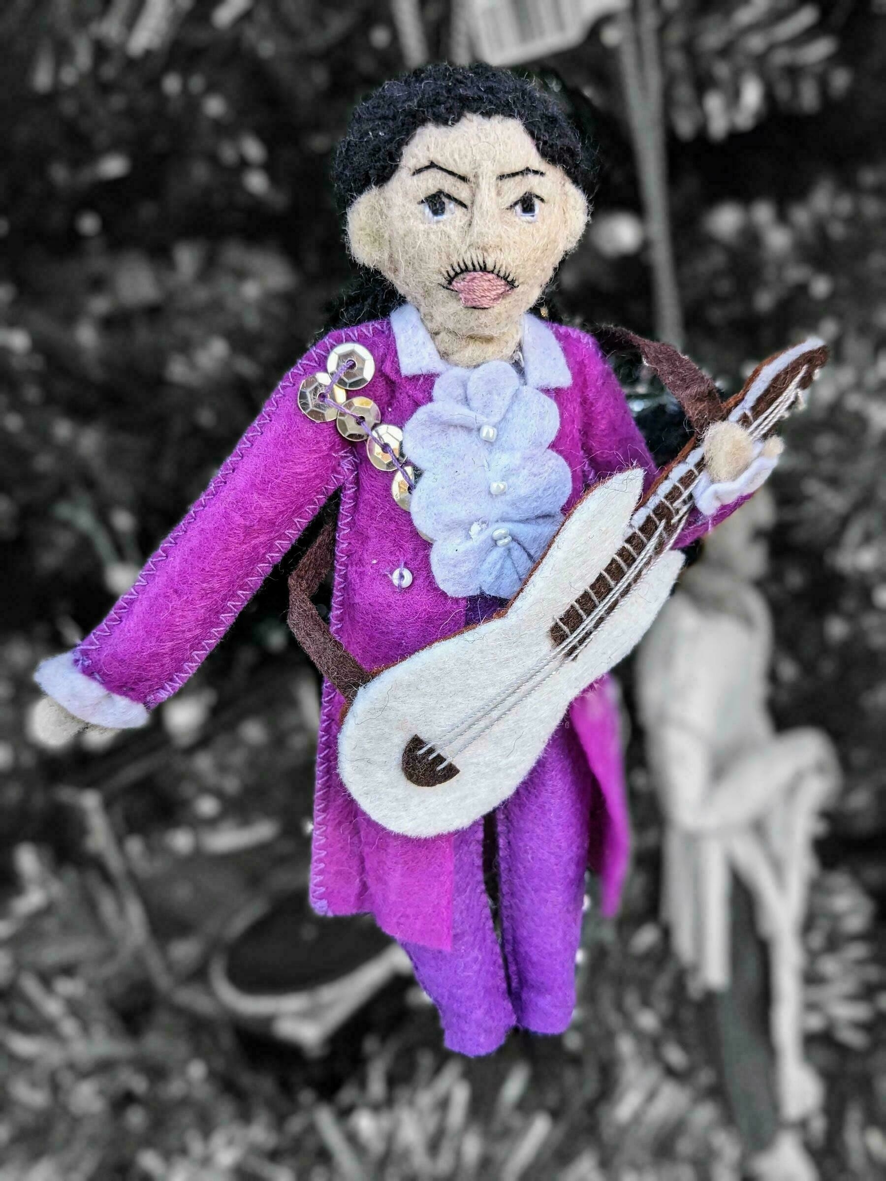 A felt ornament of the musician Prince, dressed in a vibrant purple outfit.