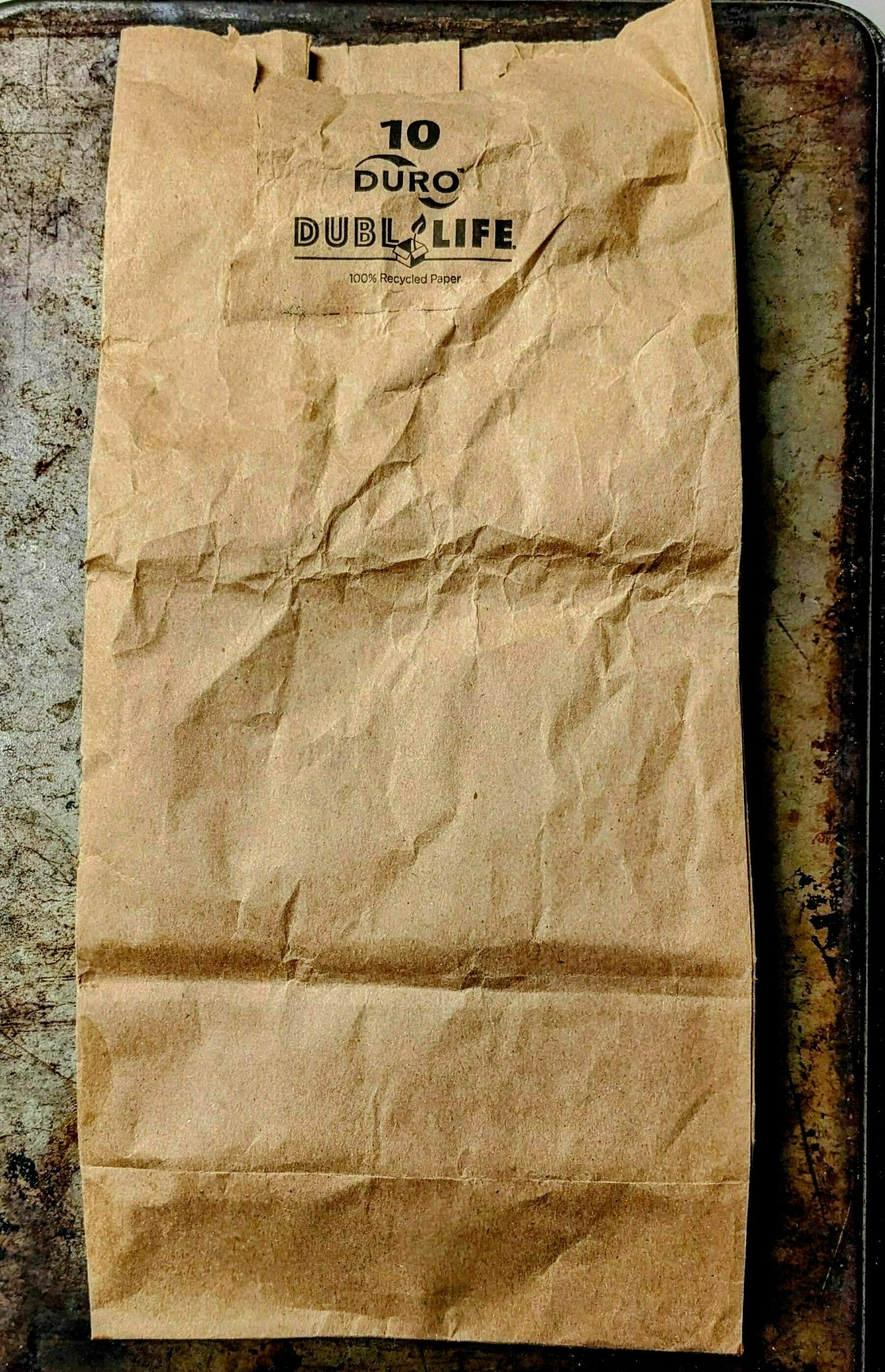 Auto-generated description: A crumpled brown paper bag with the text 10 Duro Dubl Life 100% Recycled Paper printed on it.